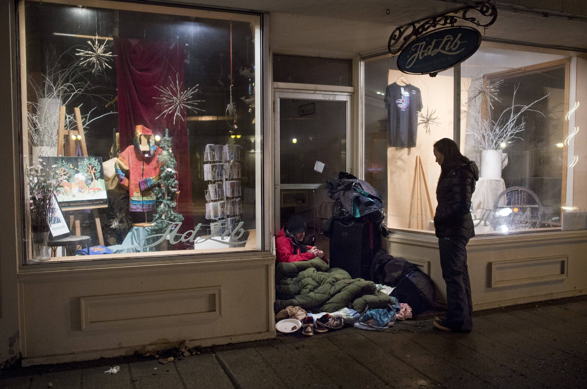 In this March 25 photo, Chloe Abbott checks in with a homeless person camping in a business doorway on South Franklin Street. (Michael Penn | Juneau Empire File)