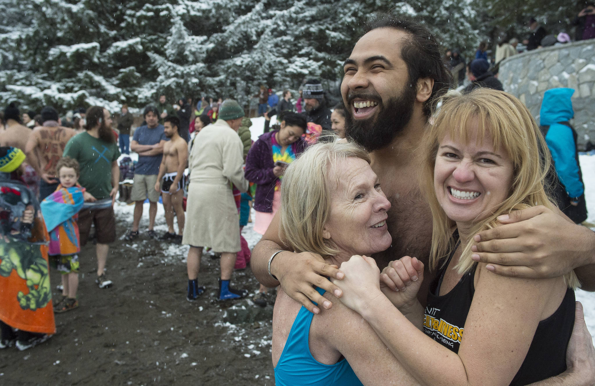 Devin Drones, Diane Bean, left, and Susan James huddle for warmth as they wait the countdown for the annual Polar Bear Dip at Auke Recreation beach on Monday, Jan. 1, 2018. (Michael Penn | Juneau Empire)
