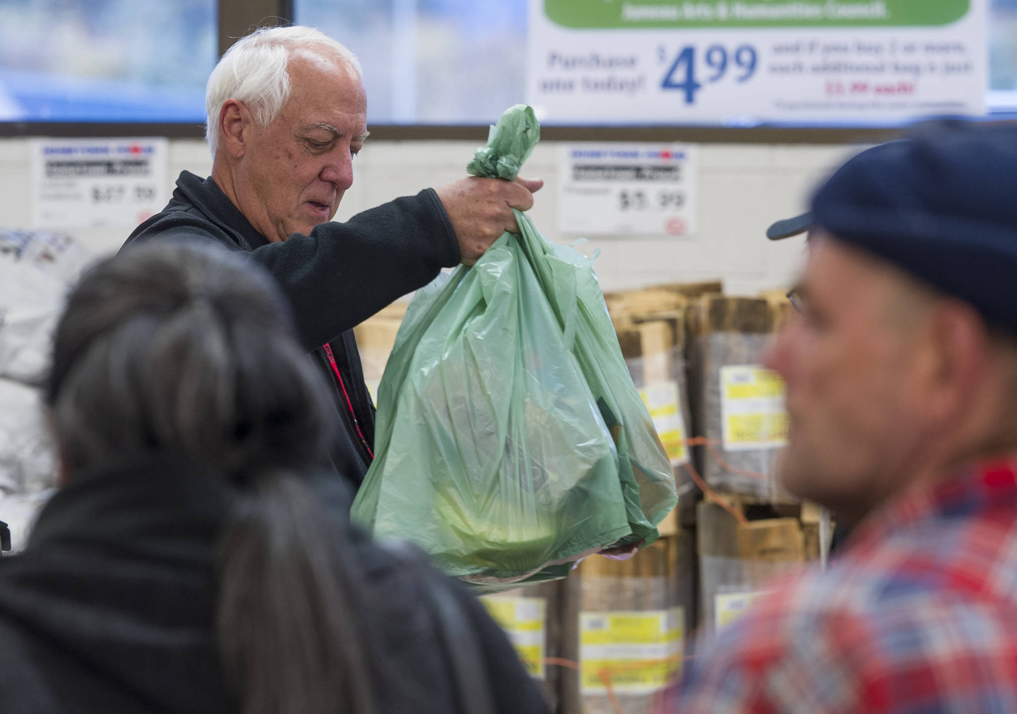 Mayor Ken Koelsch bags groceries for customers during an event at Super Bear in October 2016. (Michael Penn | Juneau Empire File)