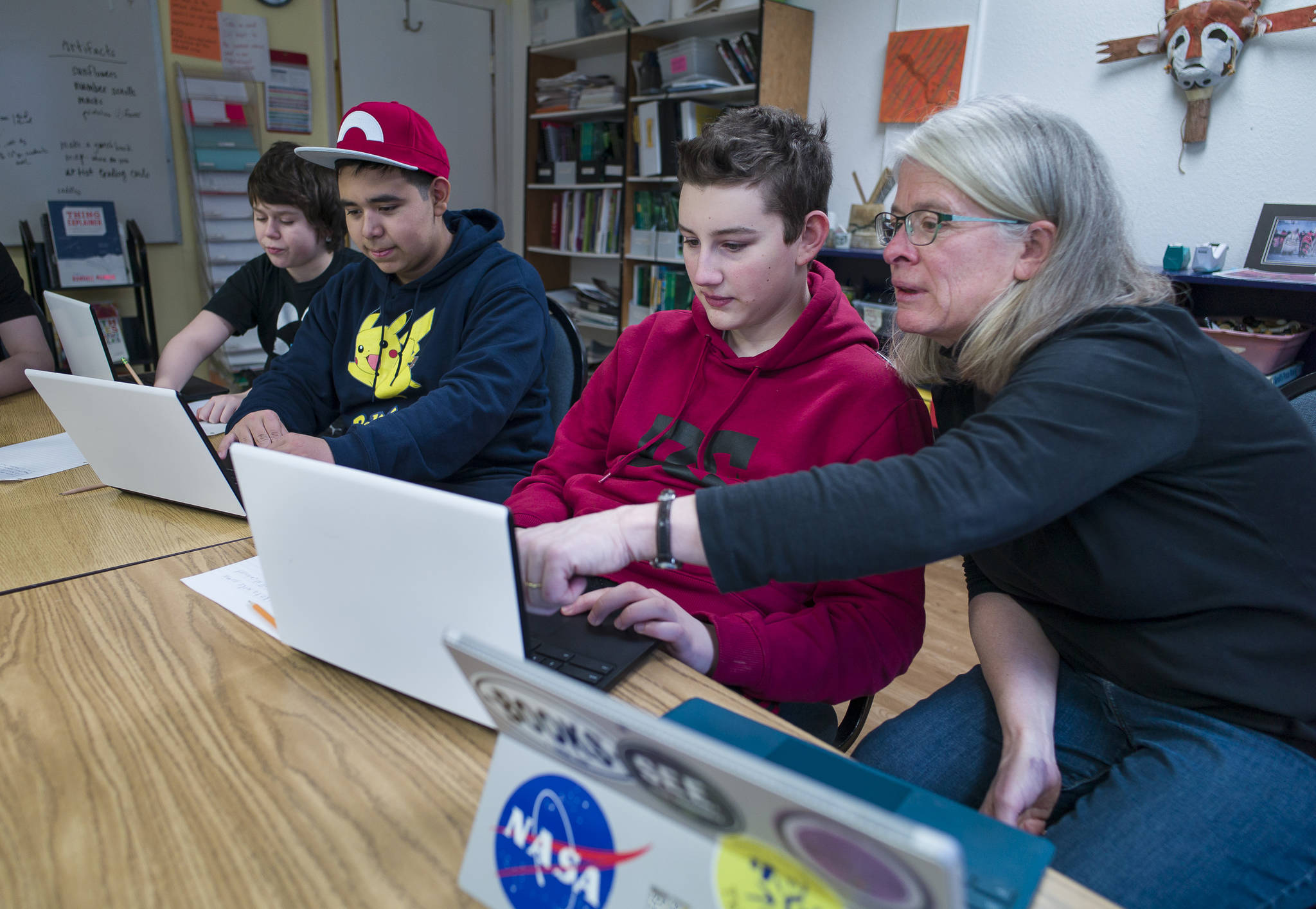Math Specialist Brenda Taylor helps eighth-graders Fisher Lee, right, and Jorge Cordero, center, and sixth-grader Joshua Kessler with their coding project at the Juneau Community Charter School on Wednesday, Jan. 10, 2018. The school is celebrating its 20th Anniversary with a dinner and presentation in the Juneau-Douglas High School commons on Saturday from 5:30 to 9 p.m. (Michael Penn | Juneau Empire)