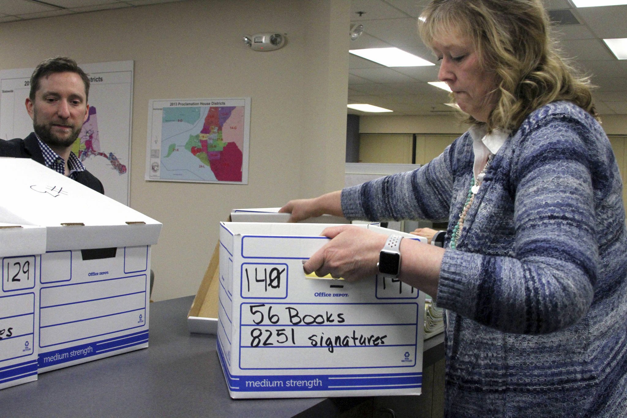 Rep. Jason Grenn, I-Anchorage, left, looks on as Carol Thompson with the state Division of Elections in Anchorage, unseals boxes containing more than 45,000 signatures, Friday, Jan. 12, 2018. Elections workers will have to verify the signatures before the measure is approved for the ballot. (Mark Thiessen | The Associated Press)