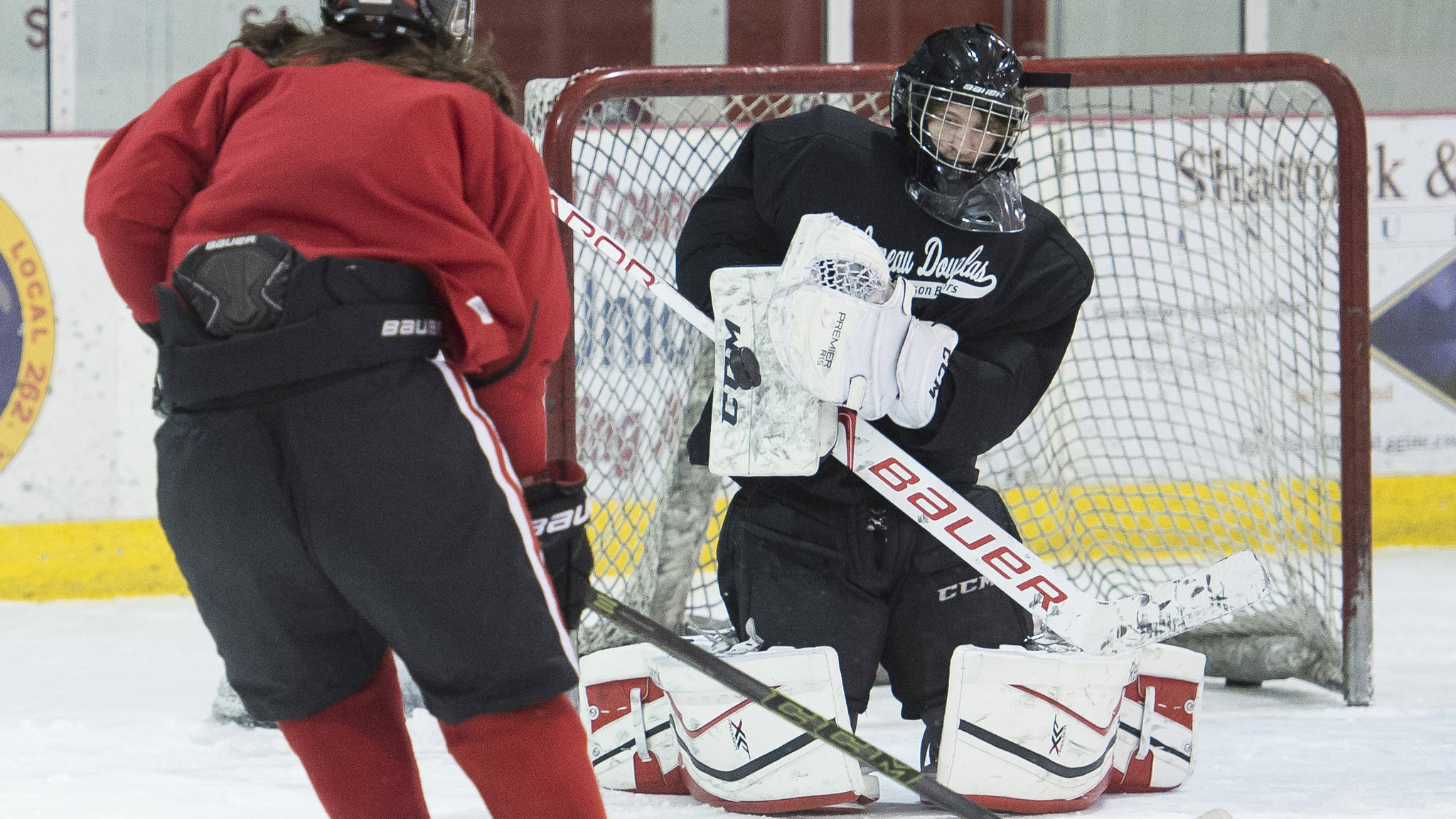 Juneau-Douglas goalie Cody Mitchell deflects a shot by Bill Bosse at a November practice at Treadwell Arena. Mitchell has started in 10 of 13 games for the Crimson Bears this season. (Michael Penn | Juneau Empire File)