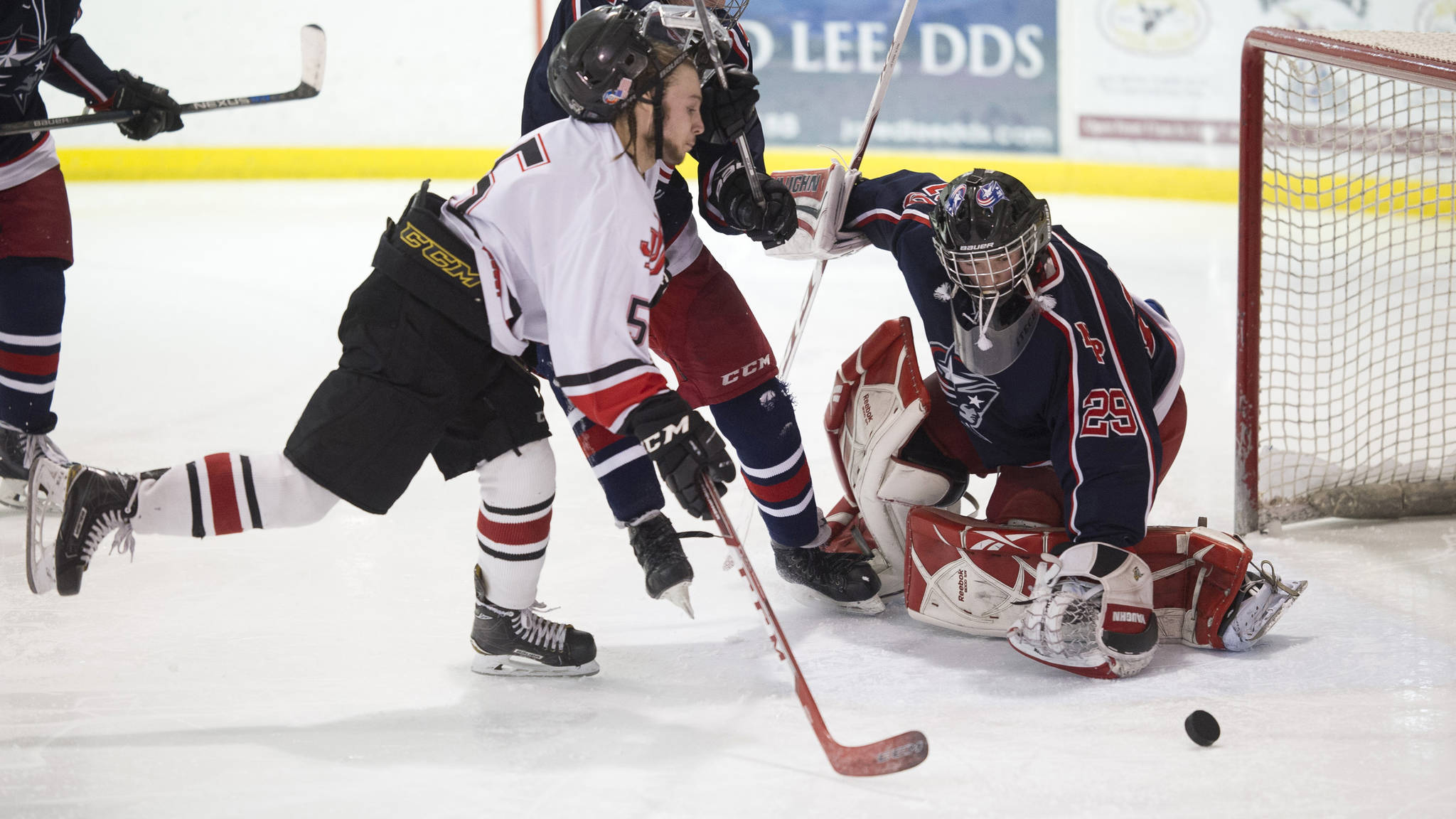 Juneau-Douglas’ Cully Corrigan scores on North Pole’s goalie Moses Halbert as his helmet is knocked away by North Pole’s Jeff Doty at Treadwell Arena on Friday, Jan. 19, 2018. (Michael Penn | Juneau Empire)