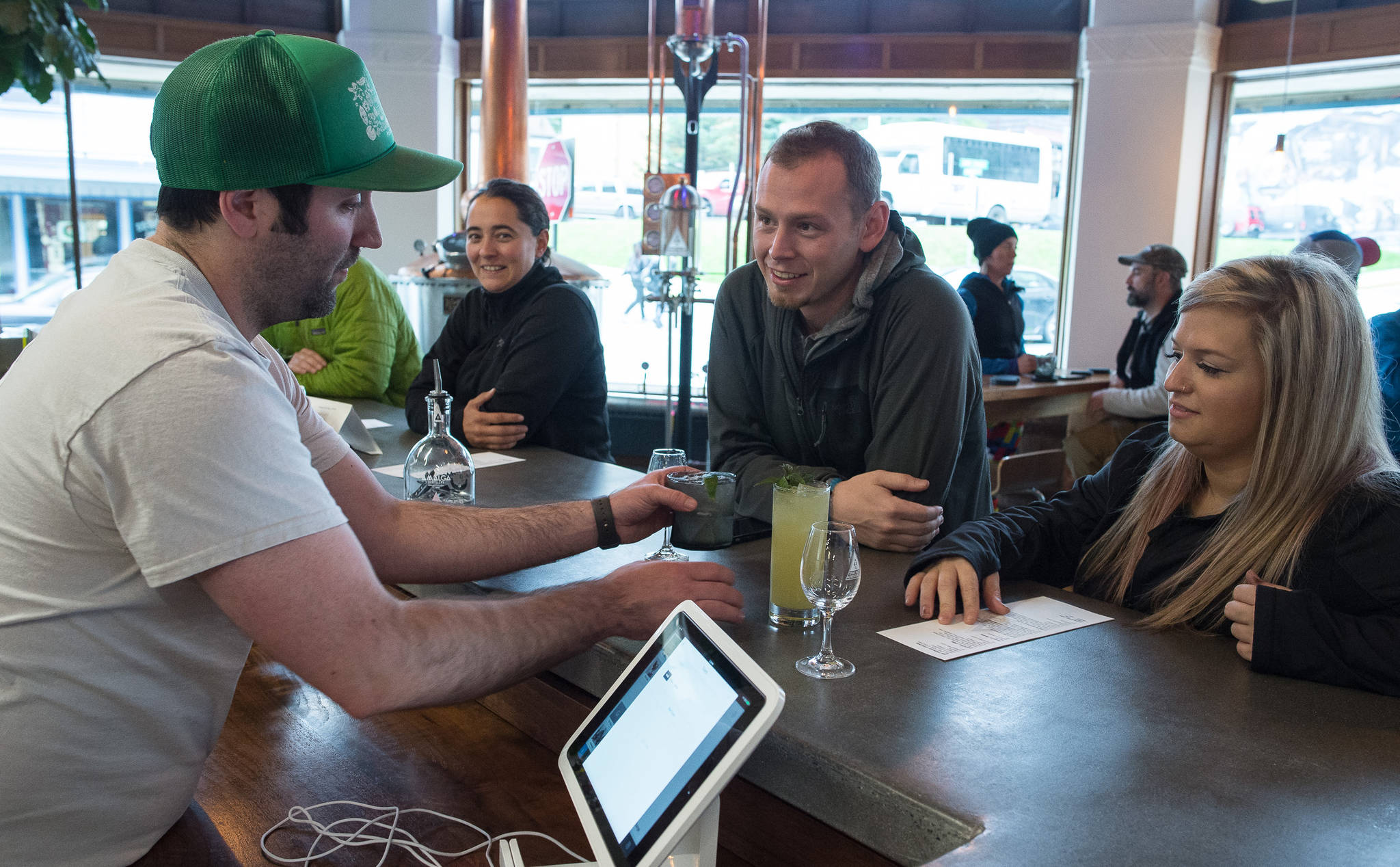 In this Sept. 14, 2017 photo, Brandon Howard, a cofounder of Amalga Distillery, left, serves mixed drinks to Nick Thein and Terra Veler at the distillery’s tasting room at Franklin and Second Streets. (Michael Penn | Juneau Empire File)