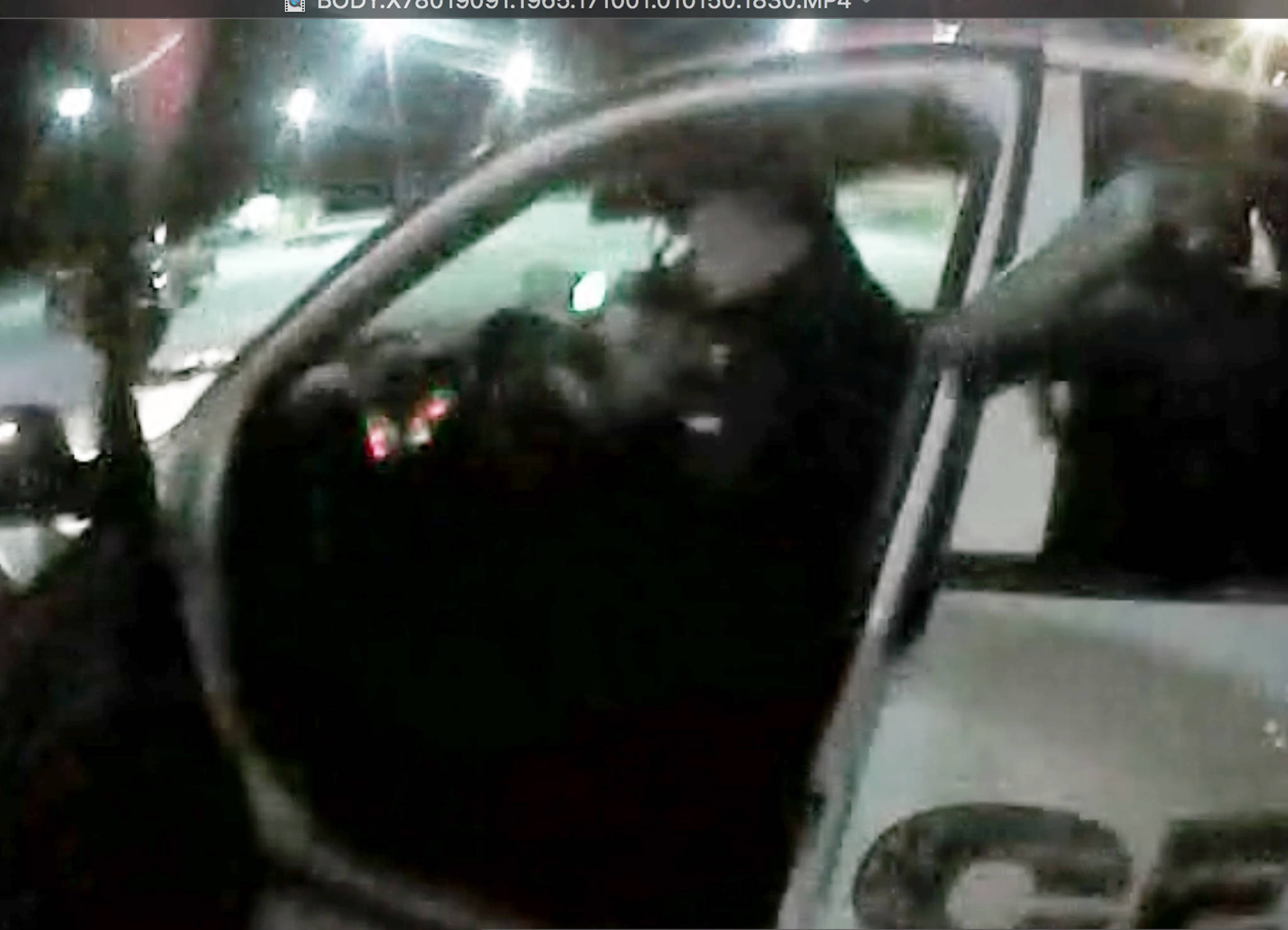 This Oct. 1, 2017 still image taken from police body camera video, provided by the city of Seward, Alaska, in response to a public records request, shows Seward Police Officer Michael “Eddie” Armstrong ordering Micah McComas out of the front seat of his patrol car, after placing him handcuffed in the back seat, during a traffic stop in Seward. Armstrong has been cleared in last year’s fatal shooting of McComas, who had been placed in the backseat of the officer’s idling patrol car and managed to start driving it away. The state attorney general’s office says in a letter to Seward police that it was reasonable for Armstrong to use deadly force. (City of Seward)