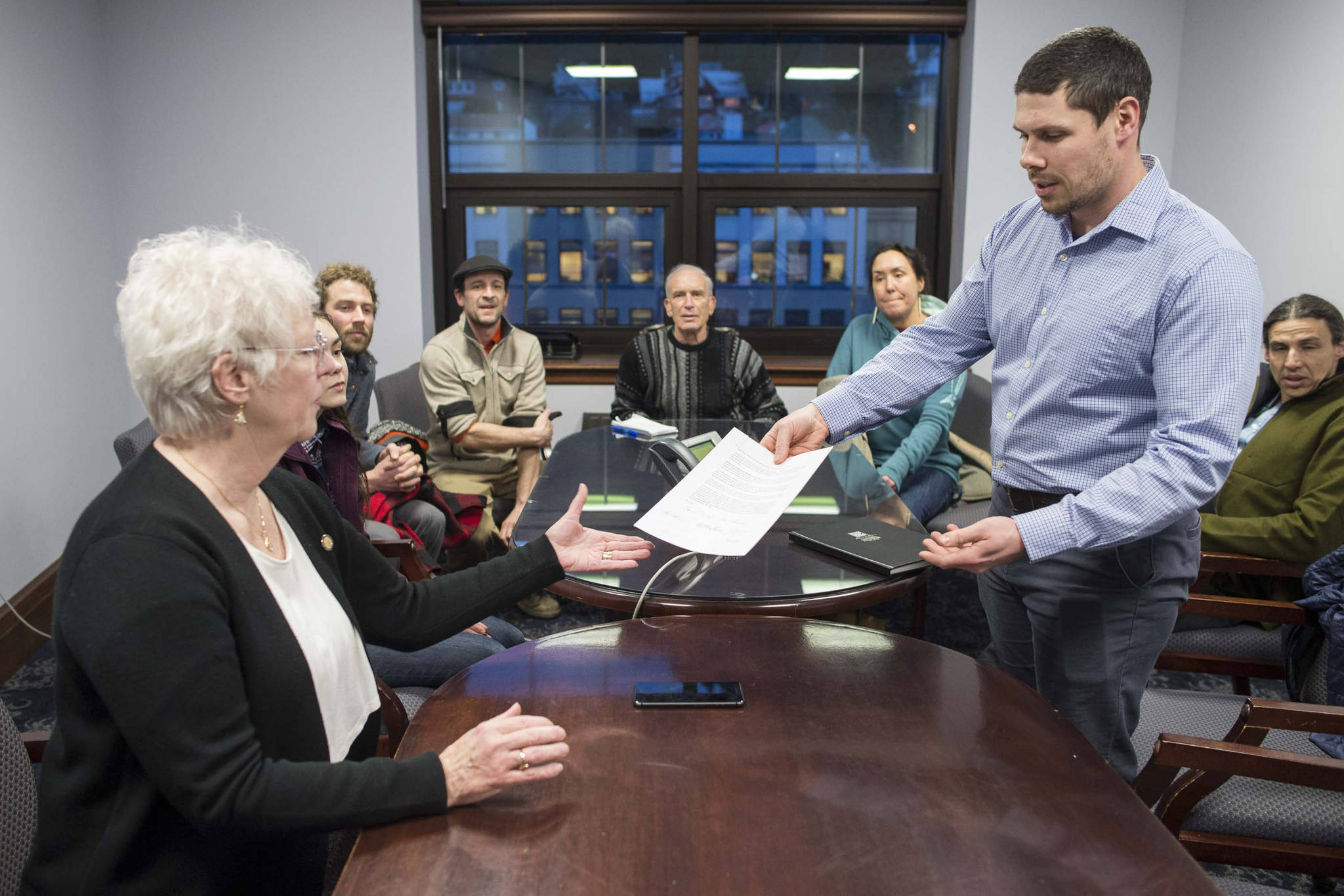 Sommers Cole, right, hands Rep. Louise Stutes, R-Kodiak a letter with other local commercial fisherman in support for her fisheries bill at the Capitol on Thursday, Feb. 1, 2018. (Michael Penn | Juneau Empire)