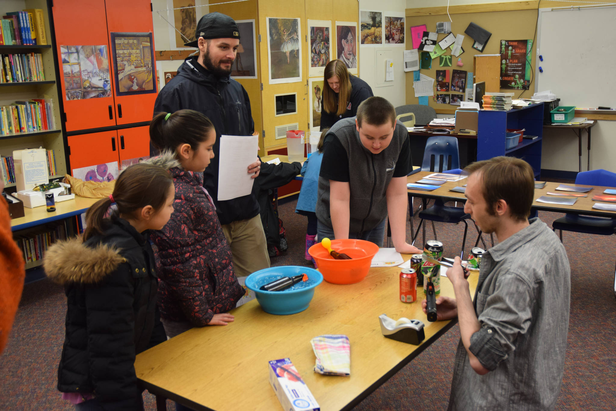 National Weather Service Meteorologist Jacob Byrd demonstrates the properties of air pressure and temperature to Harborview Elementary students Alijah Austin, left, Isabella Austin, middle, Jacob Olsen and his son Talin Branivyn Olsen at Science Night on Thursday. (Kevin Gullufsen | Juneau Empire)