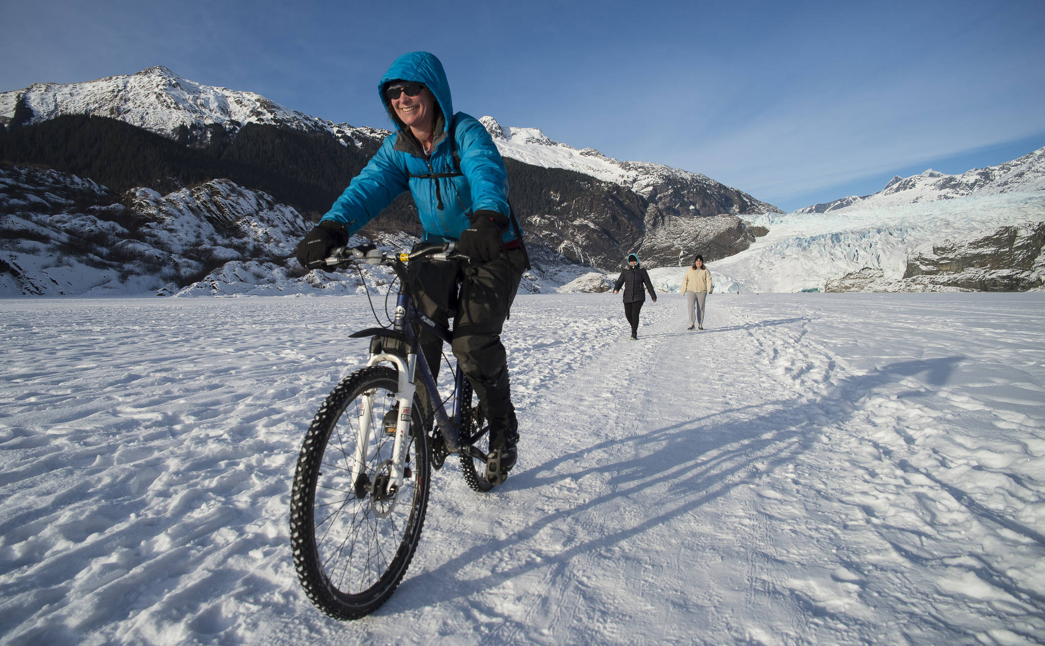Gwen Baluss rides her bike back from a visit to the Mendenhall Glacier on the frozen lake surface on Monday, Feb. 5, 2018. (Michael Penn | Juneau Empire)