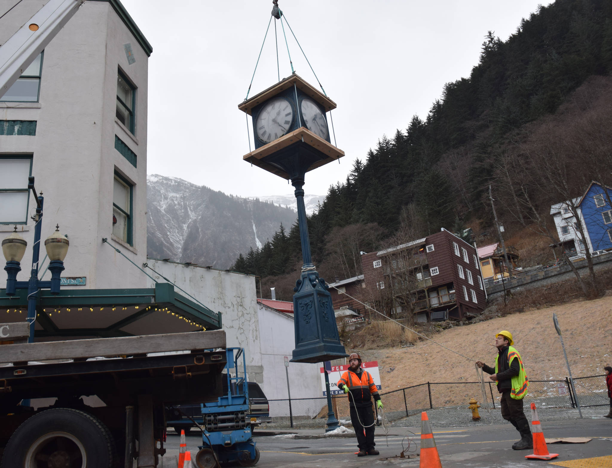 Tyler Blevins and Abe Ortega guide a clock on Front and Franklin streets as it’s hoisted onto a truck for transportation. (Kevin Gullufsen | Juneau Empire)