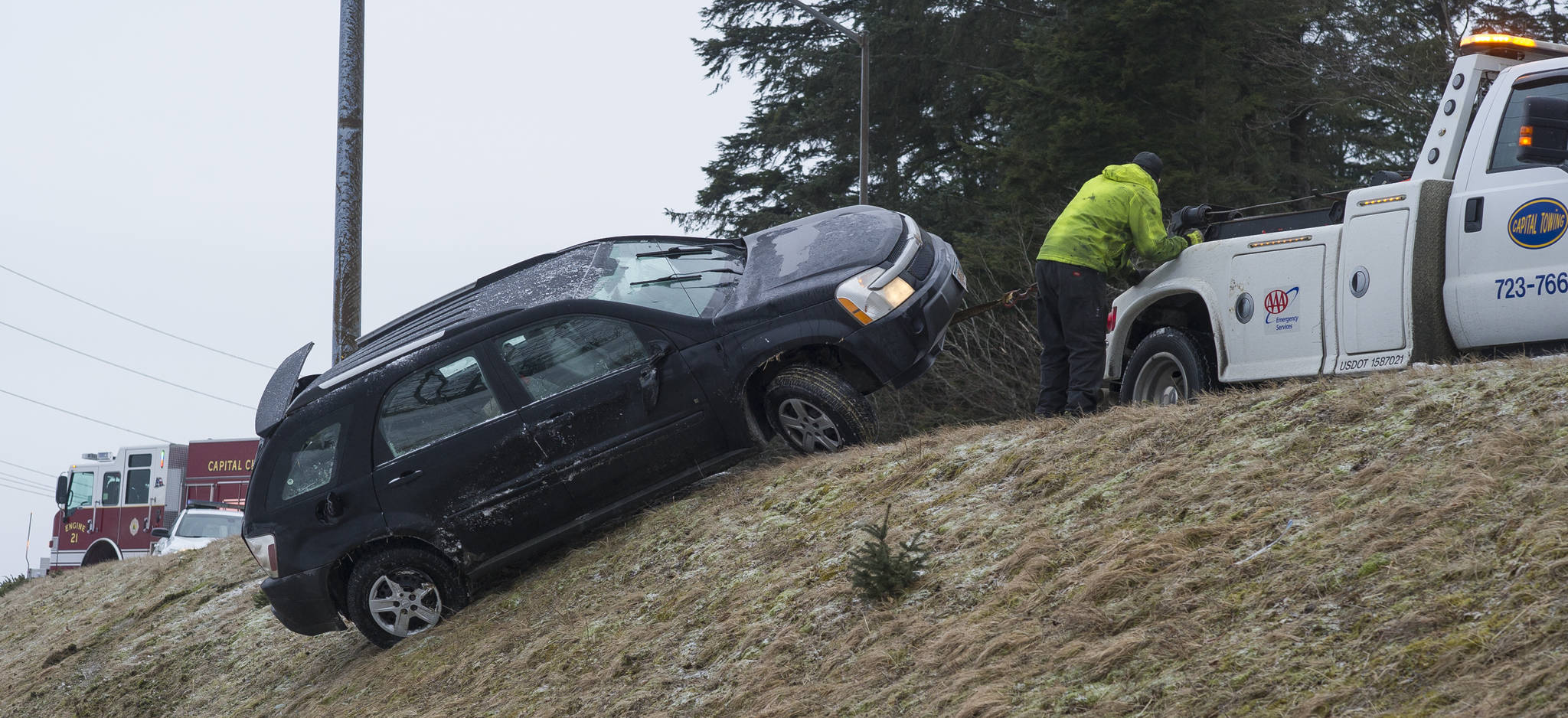 Michael Penn | Juneau Empire  A Capital Towing company employee pulls a vehicle up the embankment at Twin Lakes on Tuesday. The driver suffered minor injuries in the one vehicle accident.