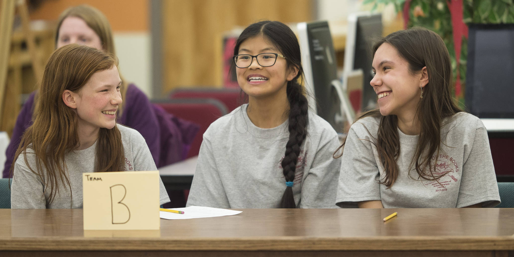 Annika Schwartz, left, Jinyue Trowsil, center, and Clara Don, all eighth grade students at Montessori Borealis, react with smiles after winning the Juneau School District final in the Battle of the Books at Floyd Dryden Middle School on Thursday, Feb. 8, 2018. (Michael Penn | Juneau Empire)