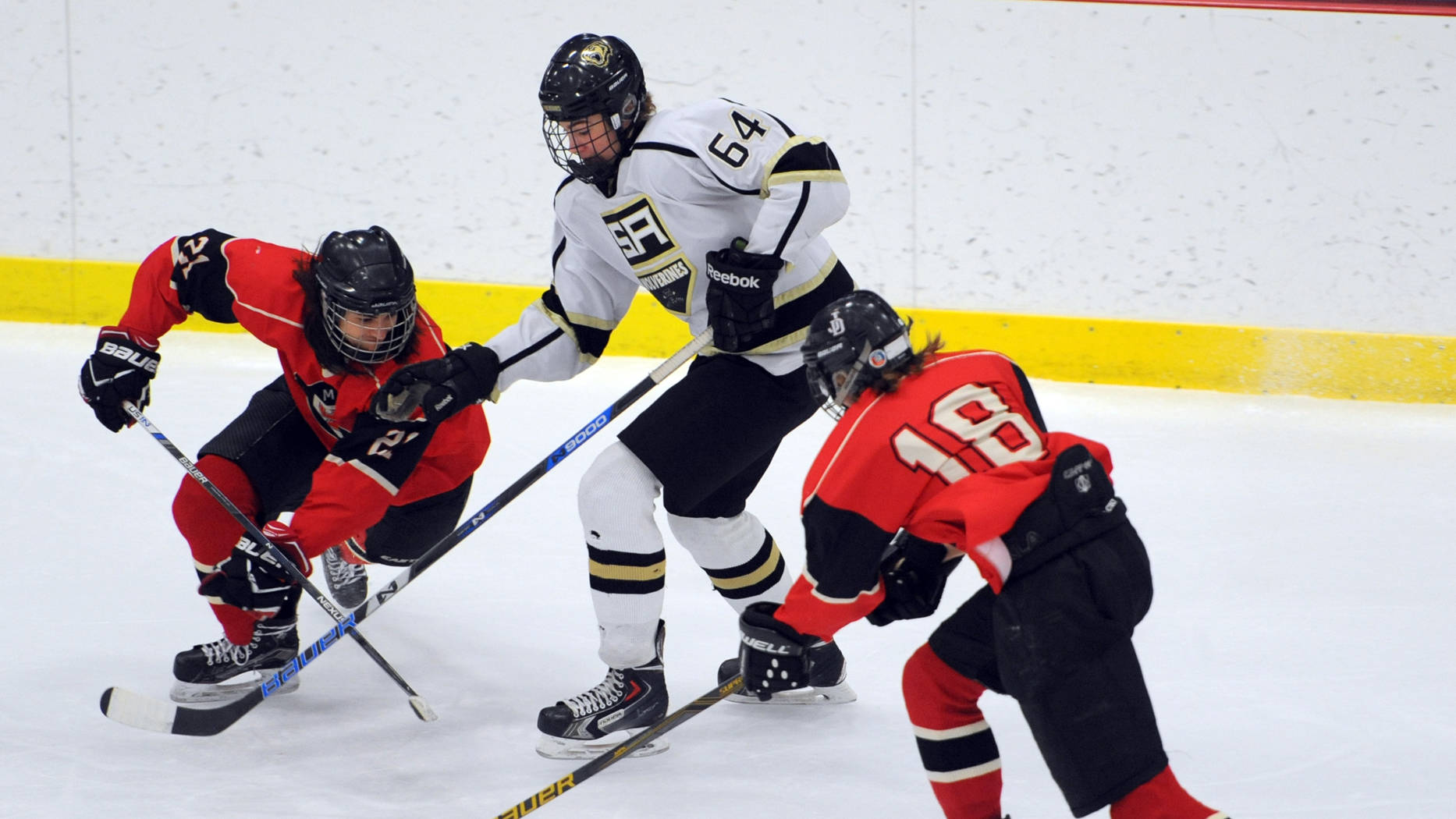 Greyson Liebelt, left, and Dalton Hoy of Juneau-Douglas defend Hayden Fox of South Anchorage during first-period action at the First National Cup state hockey tournament on February 10, 2018, in Wasilla. South Anchorage claimed a 4-1 lead after one period. (Erik Hill | For the Juneau Empire)