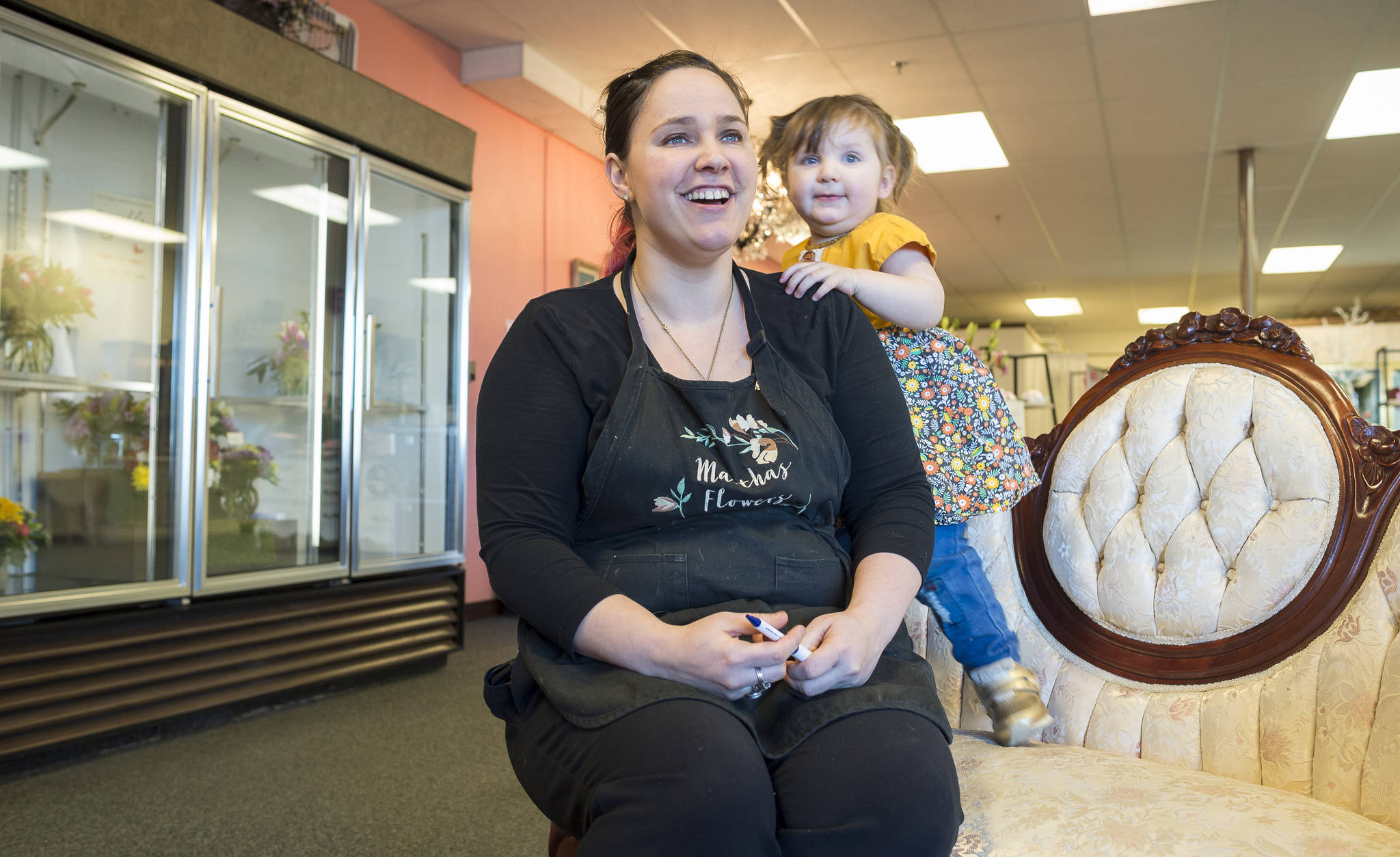 Debrah Clements, with her 19-month-old daughter, Ezmae, talks about the airport shopping district at their shop, Martha’s Flowers, in the Airport Shopping Center on Friday, Feb. 9, 2018. (Michael Penn | Juneau Empire)