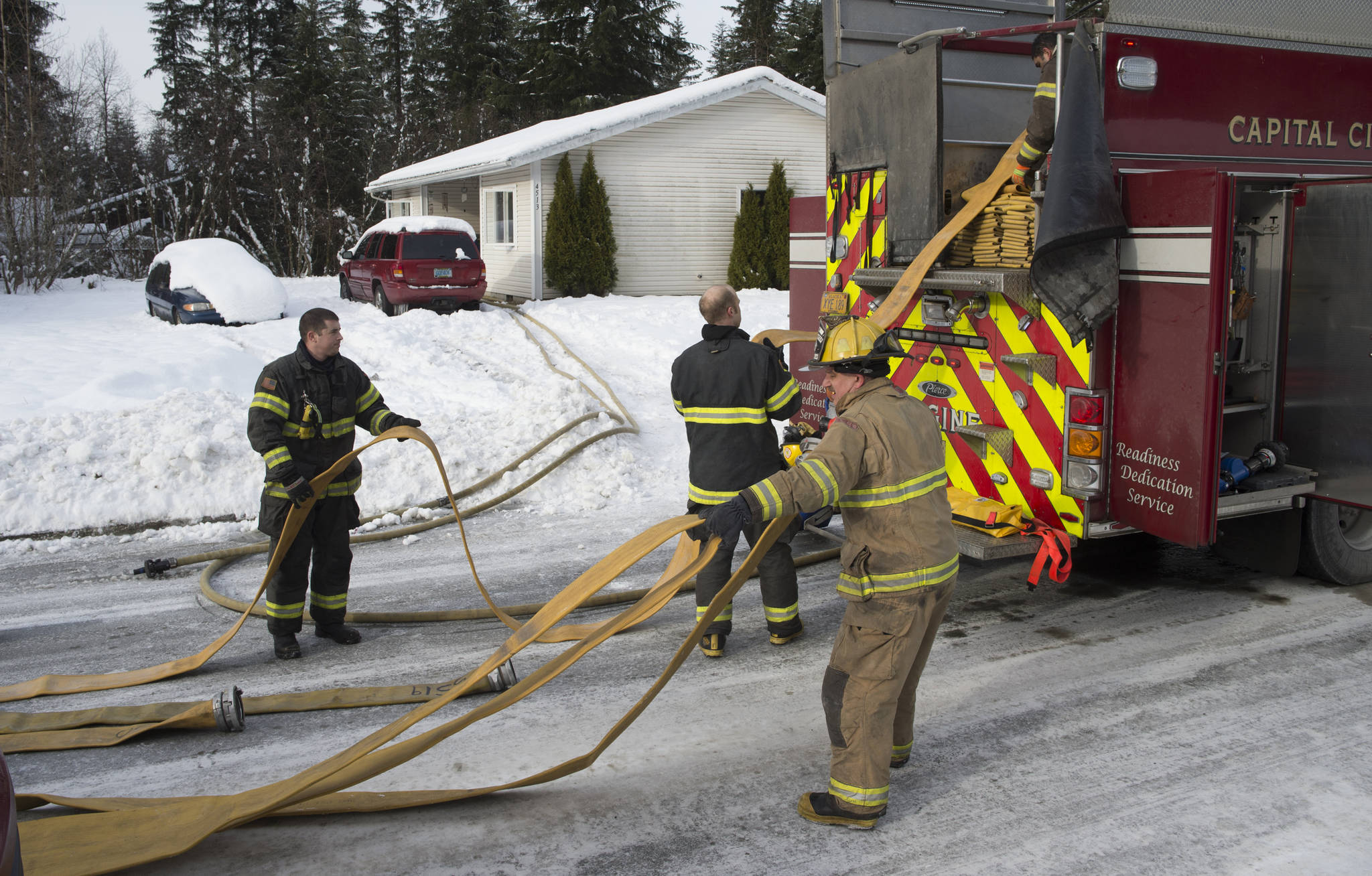 Capital City Fire/Rescue firemen pack up fire hoses after responding to a house fire at 4513 Kanata Street on Wednesday, Feb. 14, 2018. (Michael Penn | Juneau Empire)