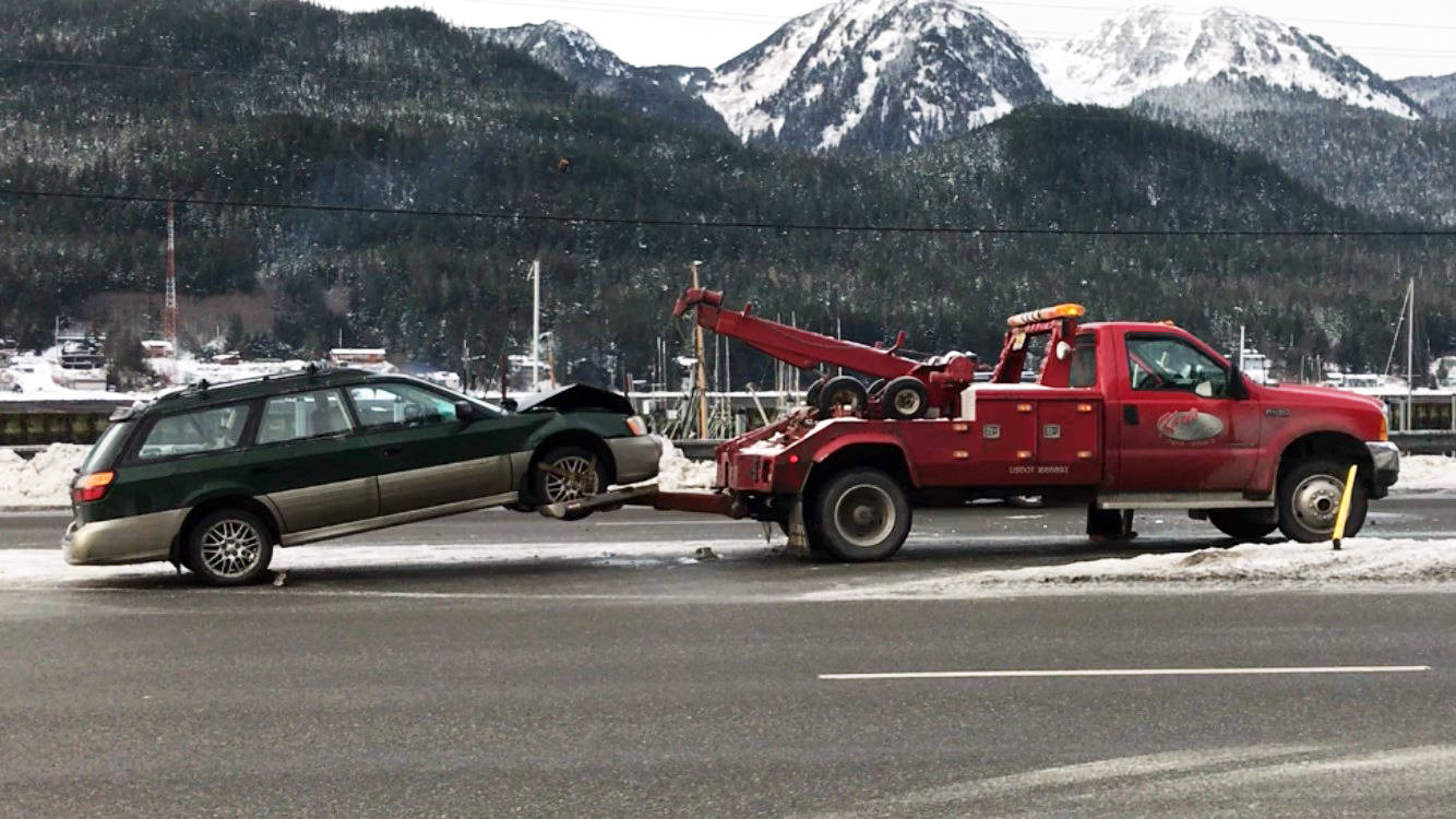 A Subaru is towed away after being hit by an SUV that slid on the ice Tuesday morning. Neither driver suffered major injuries, though the driver of the SUV was taken to the hospital as a precaution. (Alex McCarthy | Juneau Empire)