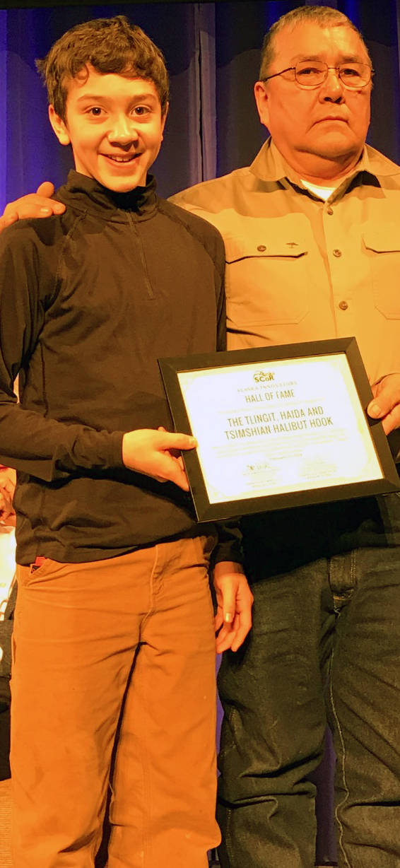 Thomas Barlow, 14, left, and his grandfather, Thomas George accept the Alaska State Committee on Research Innovators Alaska Hall of Fame award in honor of the halibut hook. The hook is the first item in the Alaska Hall Of Fame. (Gregory Philson | Juneau Empire)