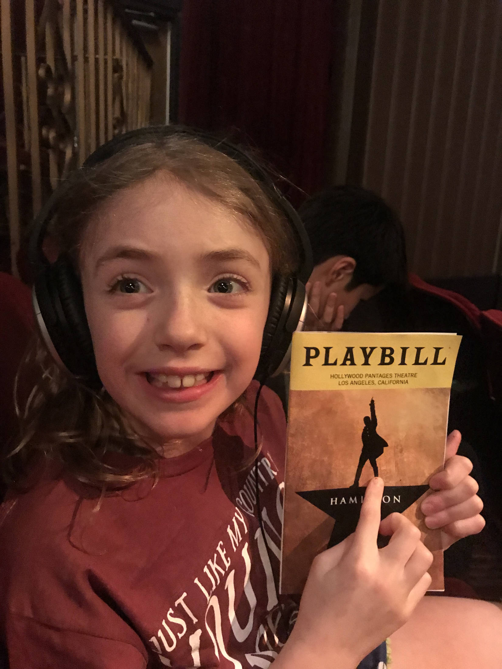 Siena Farr, with playbill, hovers an inch over her seat waiting for the show to start. Courtesy of Clint J. Farr