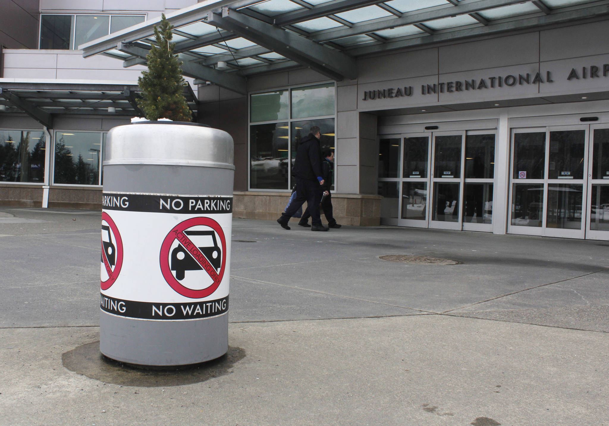A sign reminds drivers not to park in the loading area at the Juneau International Airport, as people enter the airport on Thursday, March 8, 2018. (Alex McCarthy | Juneau Empire)