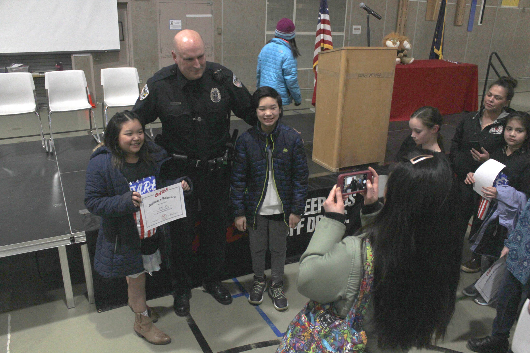 School Resource Officer Blain Hatch poses with students after a DARE graduation at Dzantik’i Heeni Middle School on Tuesday, March 13, 2018. Hatch is retiring this June. (Alex McCarthy | Juneau Empire)