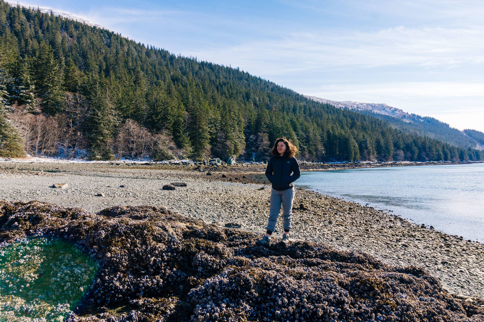 Claire Helgeson, a friend of the photographer’s, stands on rocks at the beach at the end of DuPont Trail Wednesday. (Gabe Donohoe | For the Juneau Empire)