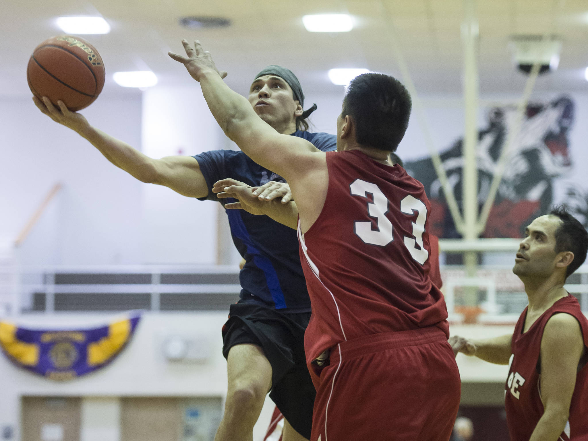 Hydaburg&rsquo;s Joe Young drives to the basket against Lance Doeake, center, and Rudy Bean in a B bracket game in the Juneau Lion&rsquo;s Gold Medal Basketball Tournament at Juneau-Douglas High School on Thursday, March 22, 2018. (Michael Penn | Juneau Empire)