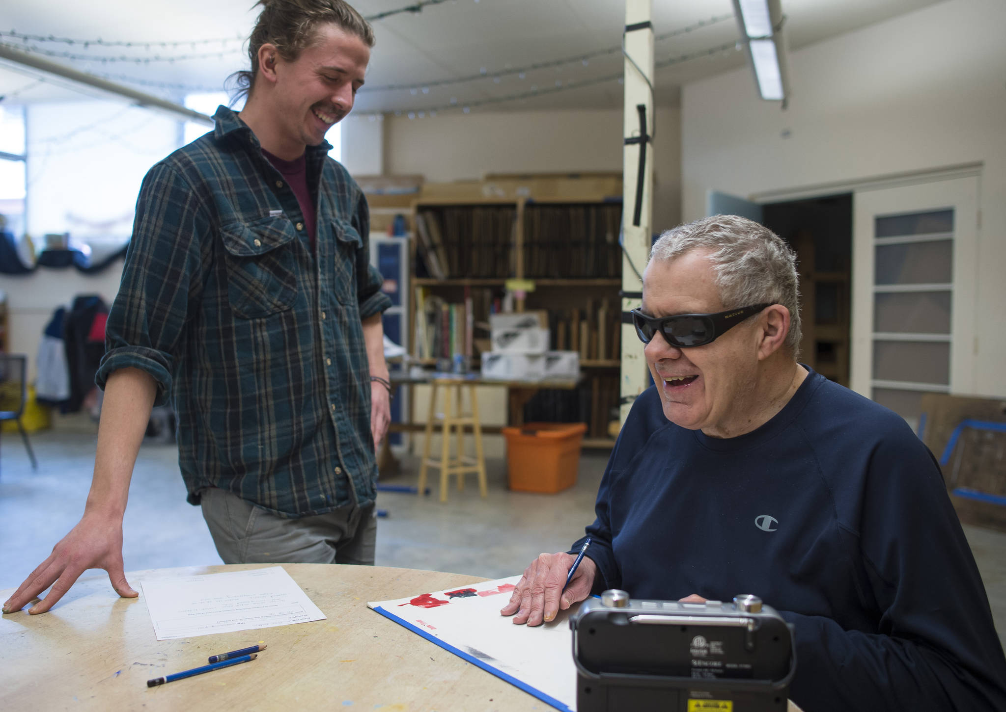 Mike Godkin, a client at REACH Inc., is helped by art studio assistant Matt Hansen during an afternoon drawing class at The Canvas on Tuesday, March 27, 2018. REACH Inc. is celebrating their 40th Anniversary. Godkin, 58, has been with REACH since it started in 1977. (Michael Penn | Juneau Empire)