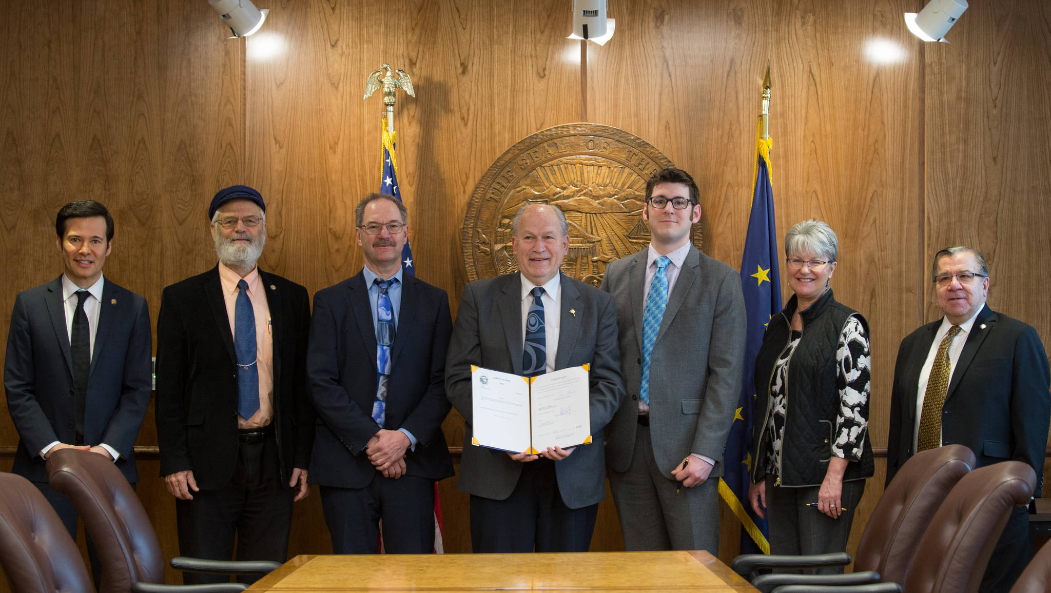From left to right, Rep. Neal Foster, D-Nome; Rep. Paul Seaton, R-Homer; David Teal of the Legislative Finance Division; Gov. Bill Walker; Neil Steininger of the Office of Management and Budget; Sen. Anna MacKinnon, R-Eagle River; and Sen. Lyman Hoffman, D-Bethel are seen at the signing ceremony for House Bill 321 on Tuesday, March 27, 2018 in the governor’s cabinet room of the Alaska State Capitol. (Drew Cason | Alaska House Majority)