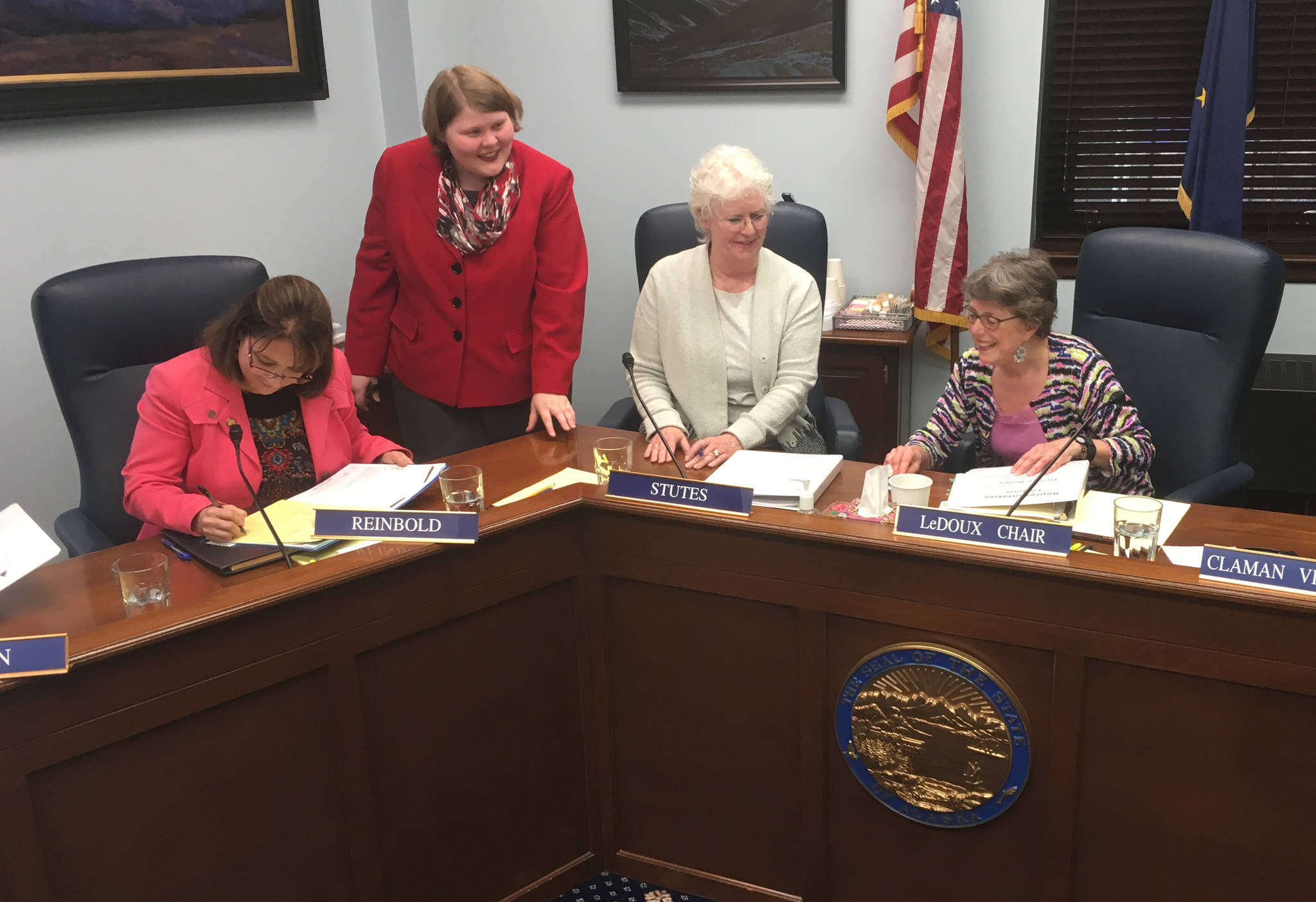 Rep. Lora Reinbold, R-Eagle River, signs a committee report on Senate Bill 63 late Tuesday, April 10, 2018 in the Alaska State Capitol. Also pictured are a legislative staffer (standing), Rep. Louise Stutes, R-Kodiak (center) and Rep. Gabrielle LeDoux, R-Anchorage (right). (James Brooks | Juneau Empire)