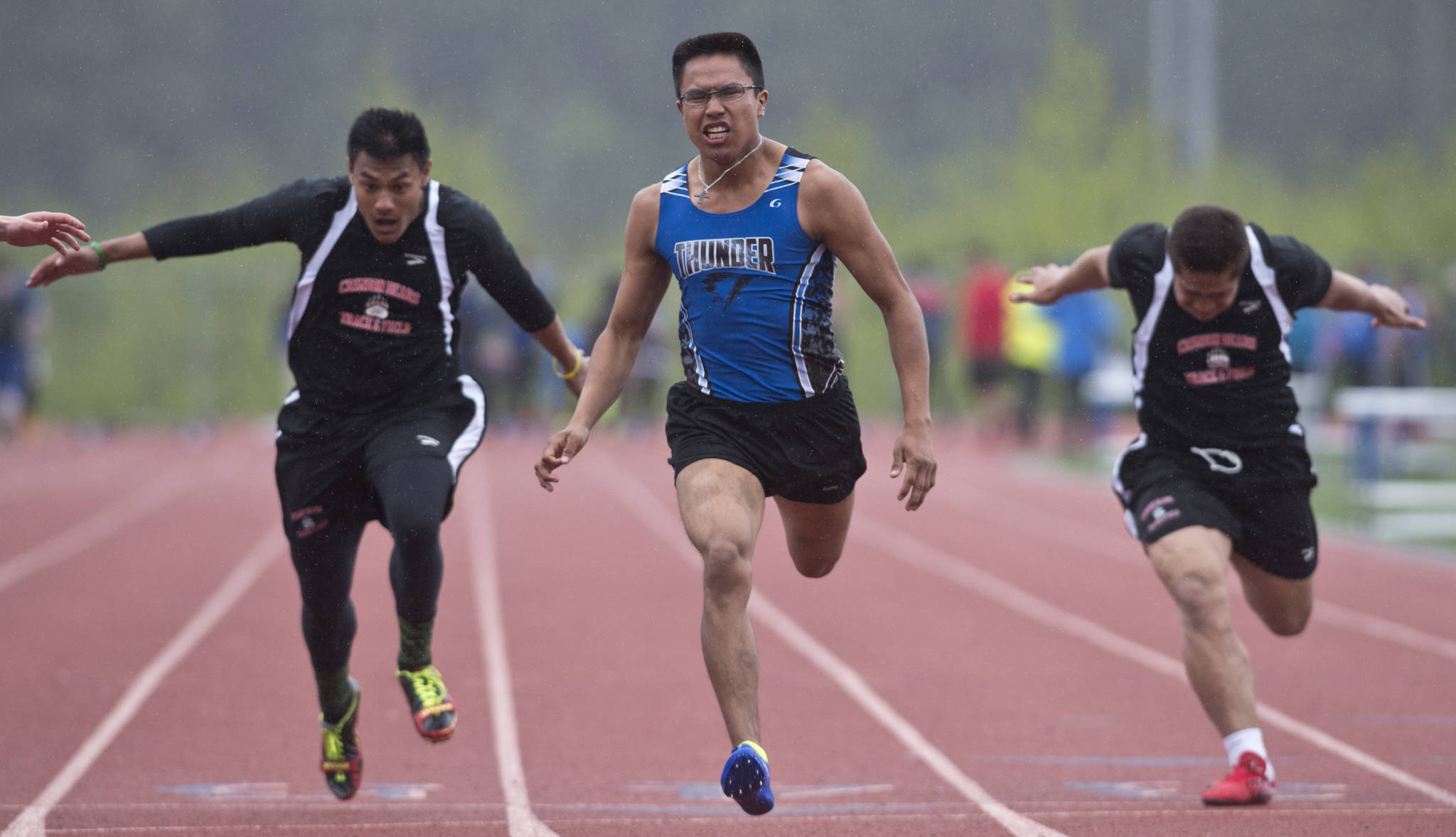 Thunder Mountain’s Erick Whisenant, center, pushes ahead of Juneau-Douglas’ Ulyx Bohulano, left, and Lance Fenumiai in a preliminary 100-meter dash at the Region V Track and Field meet at Thunder Mountain High School on May 19, 2017. (Michael Penn | Juneau Empire File)