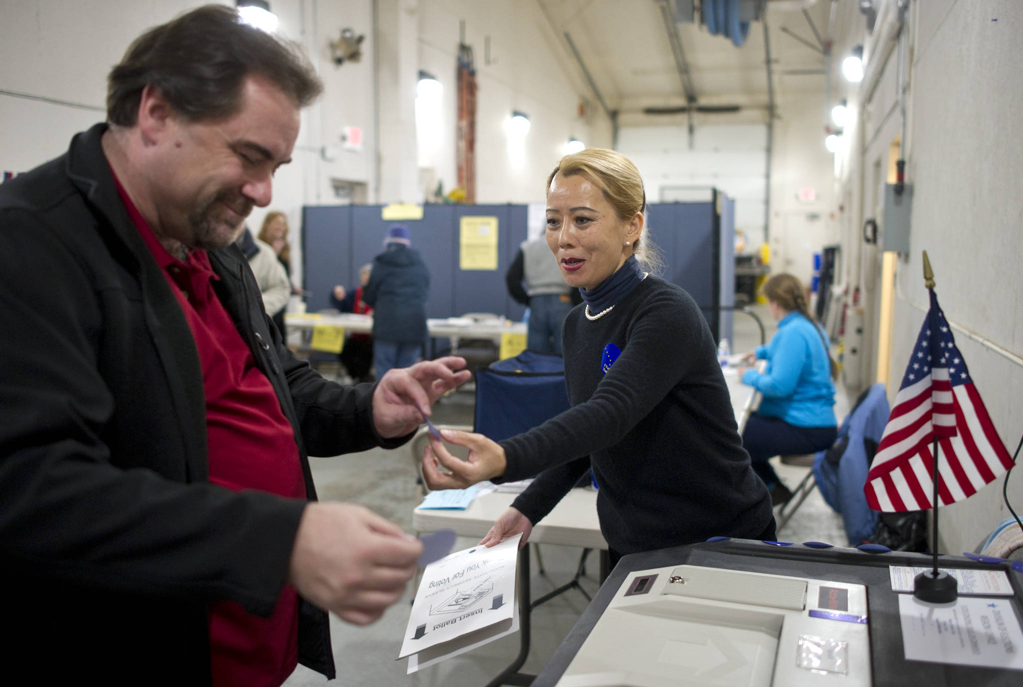 In this Nov. 8, 2016 photo, election volunteer Lily Hong Campbell hands William Grooms a voter sticker after he cast his ballot at AEL&P. (Michael Penn | Juneau Empire File)