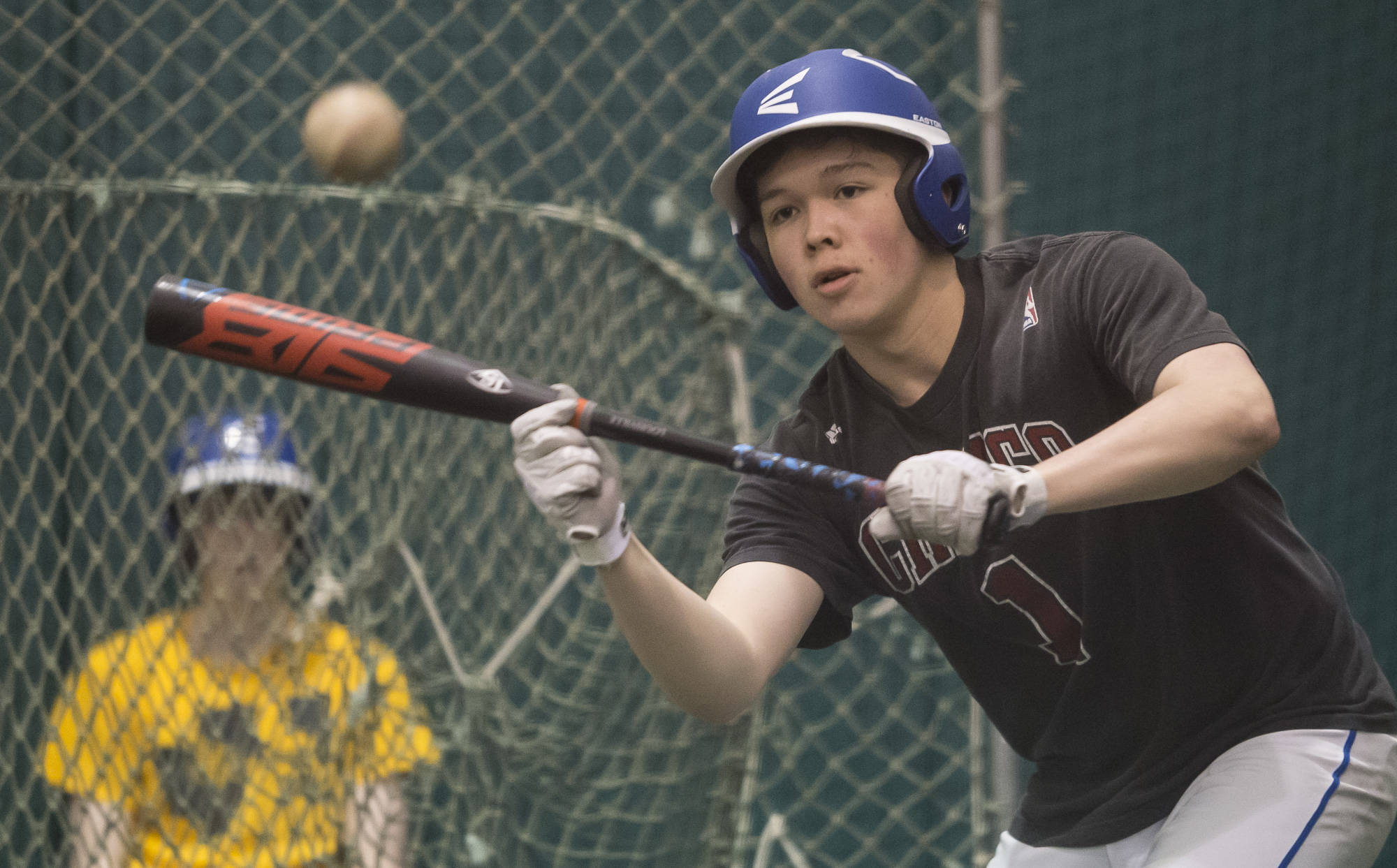 Senior Sammy McKnight works on his bunting skills as junior Cameron Eppers, background, waits his turn during Thunder Mountain High School baseball practice at the Wells Fargo Dimond Park Fieldhouse on Tuesday, April 24, 2018. (Michael Penn | Juneau Empire)