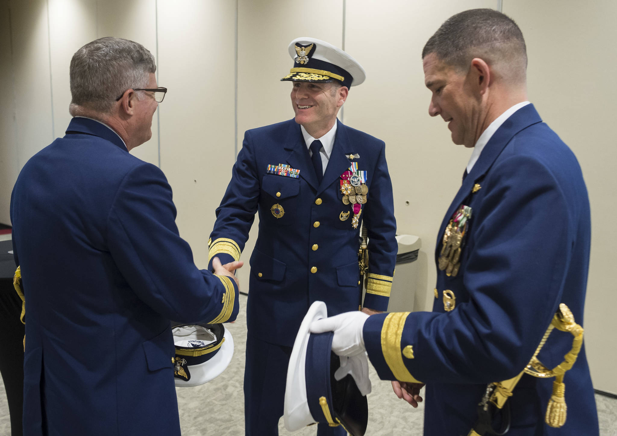 Vice Admiral Fred M. Midgette, Commander of Pacific Area and Coast Guard Defense Force West, left, Rear Admiral Michael F. McAllister, outgoing Commander of the Coast Guard 17th District, center, and Rear Admiral Matthew T. Bell Jr., incoming Commander of the Coast Guard 17th District, shake hands after a Change of Command Ceremony for the U.S. Coast Guard 17th District at the Elizabeth Peratrovich Hall on Wednesday, May 9, 2018. (Michael Penn | Juneau Empire)