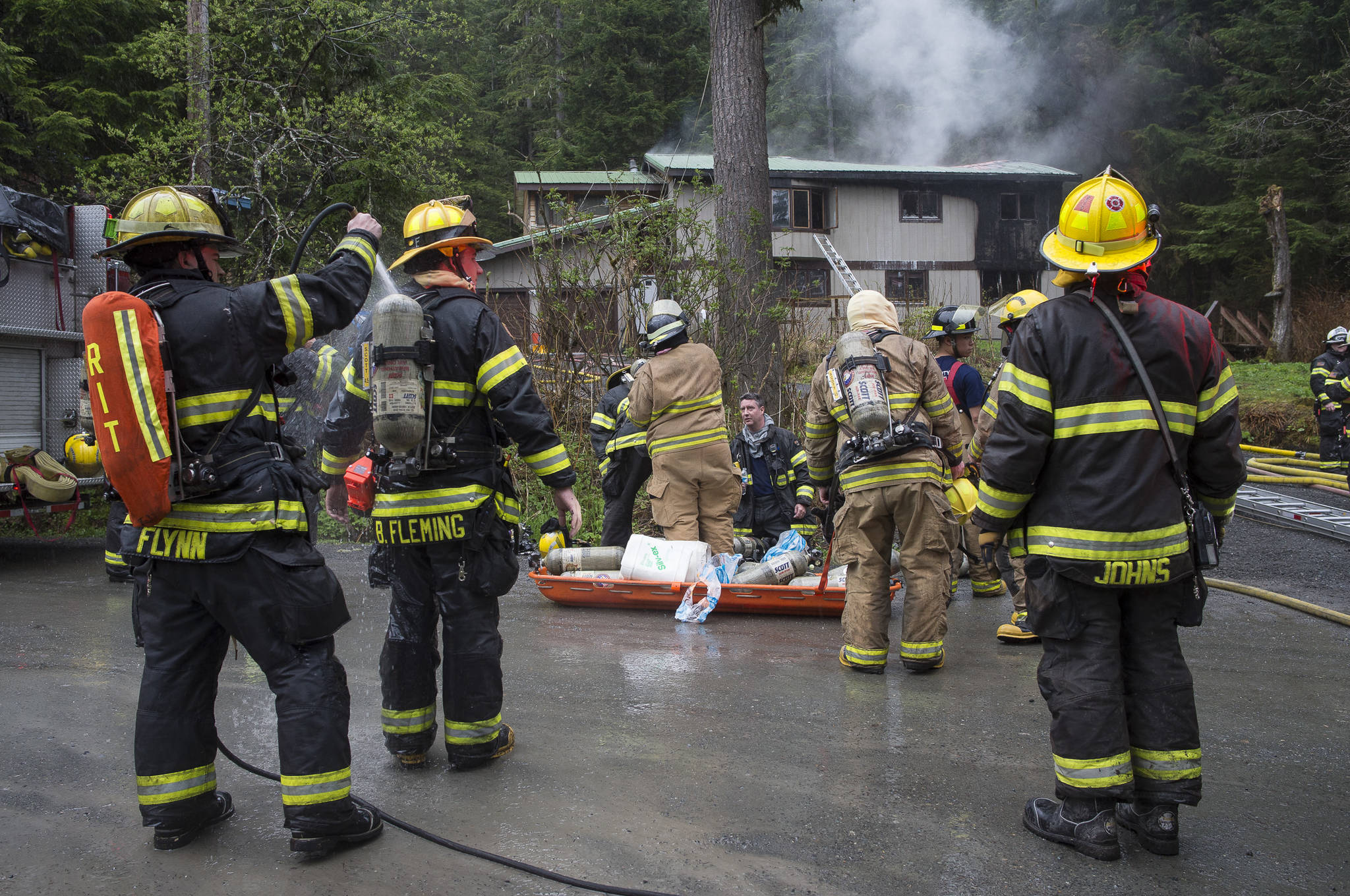 Capital City Fire/Rescue personnel respond to a house fire at 19140 Randall Road on Friday, May 11, 2018. According to Chuck Collins the house was recently bought by his daughter, Brooke, and her husband, Kevin Walker. Collins said the fire started in the attached apartment. (Michael Penn | Juneau Empire)