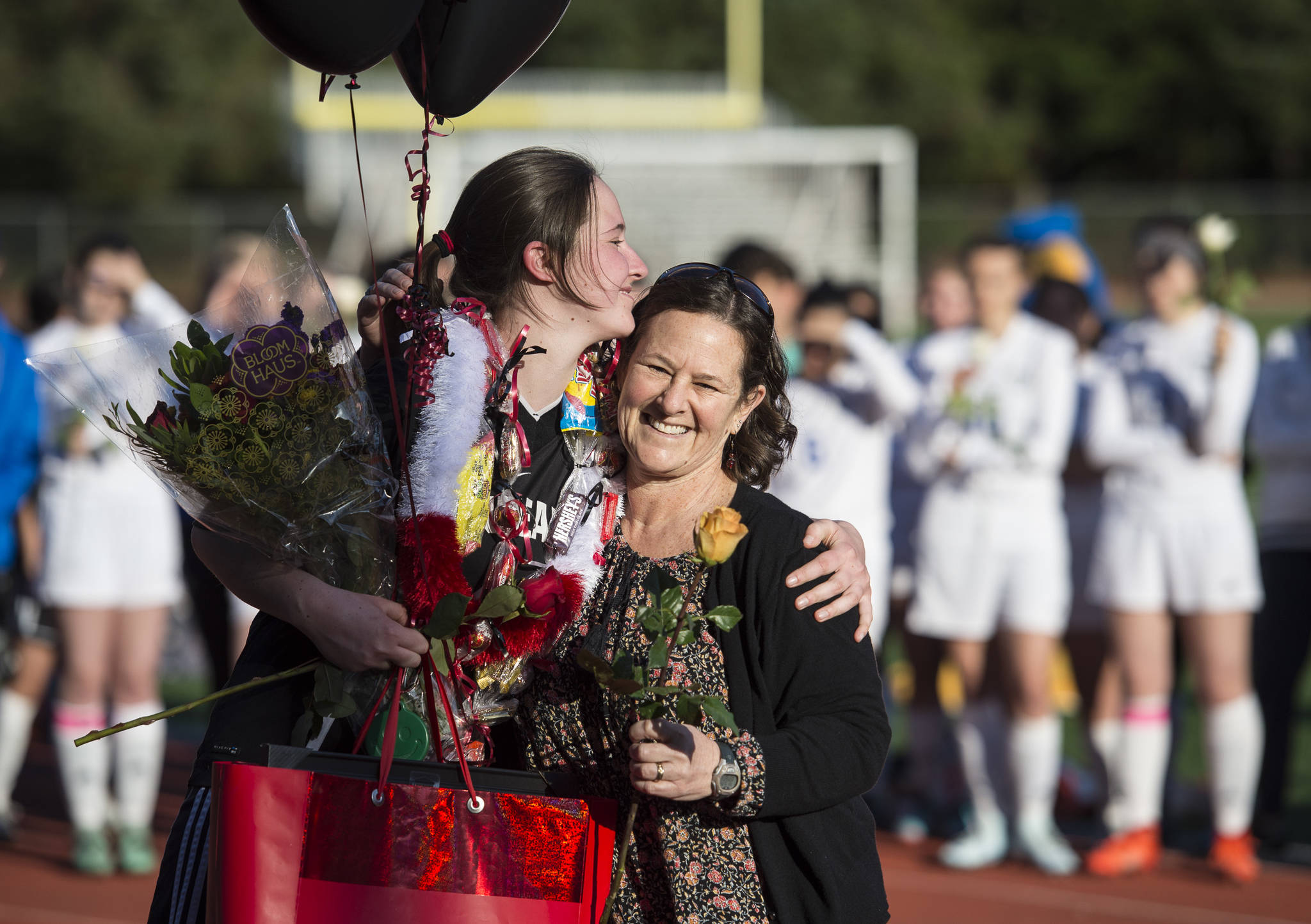 Juneau-Douglas’ Bianca Eagan receives gifts from her mother, Cynthia, for Senior Night at Adair-Kennedy Memorial Park on Tuesday, May 15, 2018. (Michael Penn | Juneau Empire)