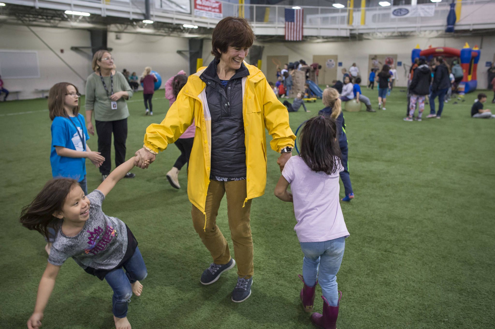 Principal Michelle Byer gives fifth-graders Ethen Etheridge, and Jesse Langel high-fives as kindergartener Janesa Johnson-Ozell looks on during Riverbend Elementary School’s outing to the Dimond Park Fieldhouse on Monday, May 21, 2018. Byer is retiring after four years at the school. (Michael Penn | Juneau Empire)
