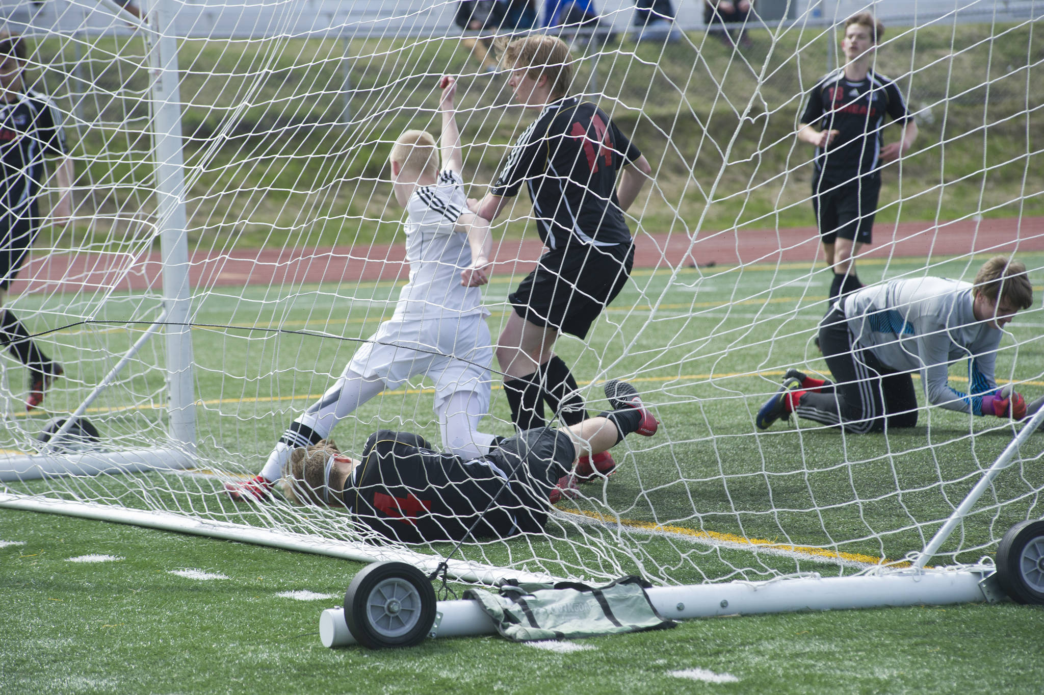 Kenai Central High School’s Leif Lofquist celebrates his goal as Juneau-Douglas High School’s Will Hoover, bottom, and Ezra Geselle, middle, follow him into the net in the ASAA Division II boys soccer state championship game on Saturday, May 26, 2018, at Service High School in Anchorage. (Nolin Ainsworth | Juneau Empire)