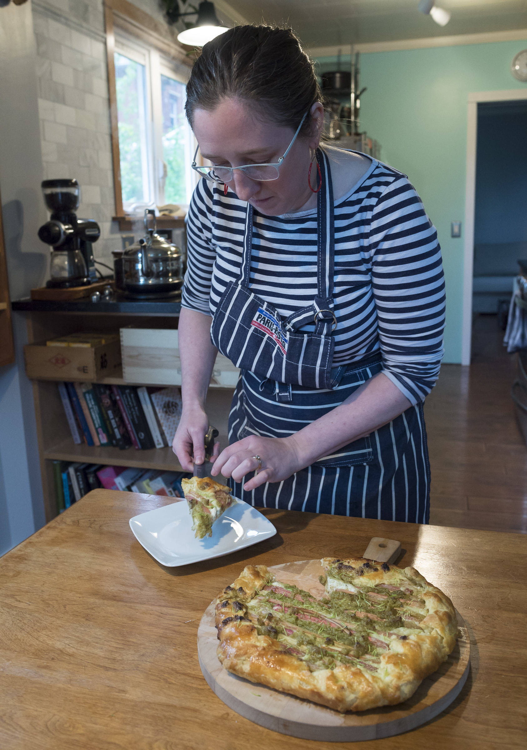 Erin Anais Heist, author of a new cooking column called “Eating Wild” for the Juneau Empire, dishes a slice of her galette made with with rhubarb, spruce tip and ricotta cheese in her home kitchen on Monday, May 21, 2018. (Michael Penn | Juneau Empire)