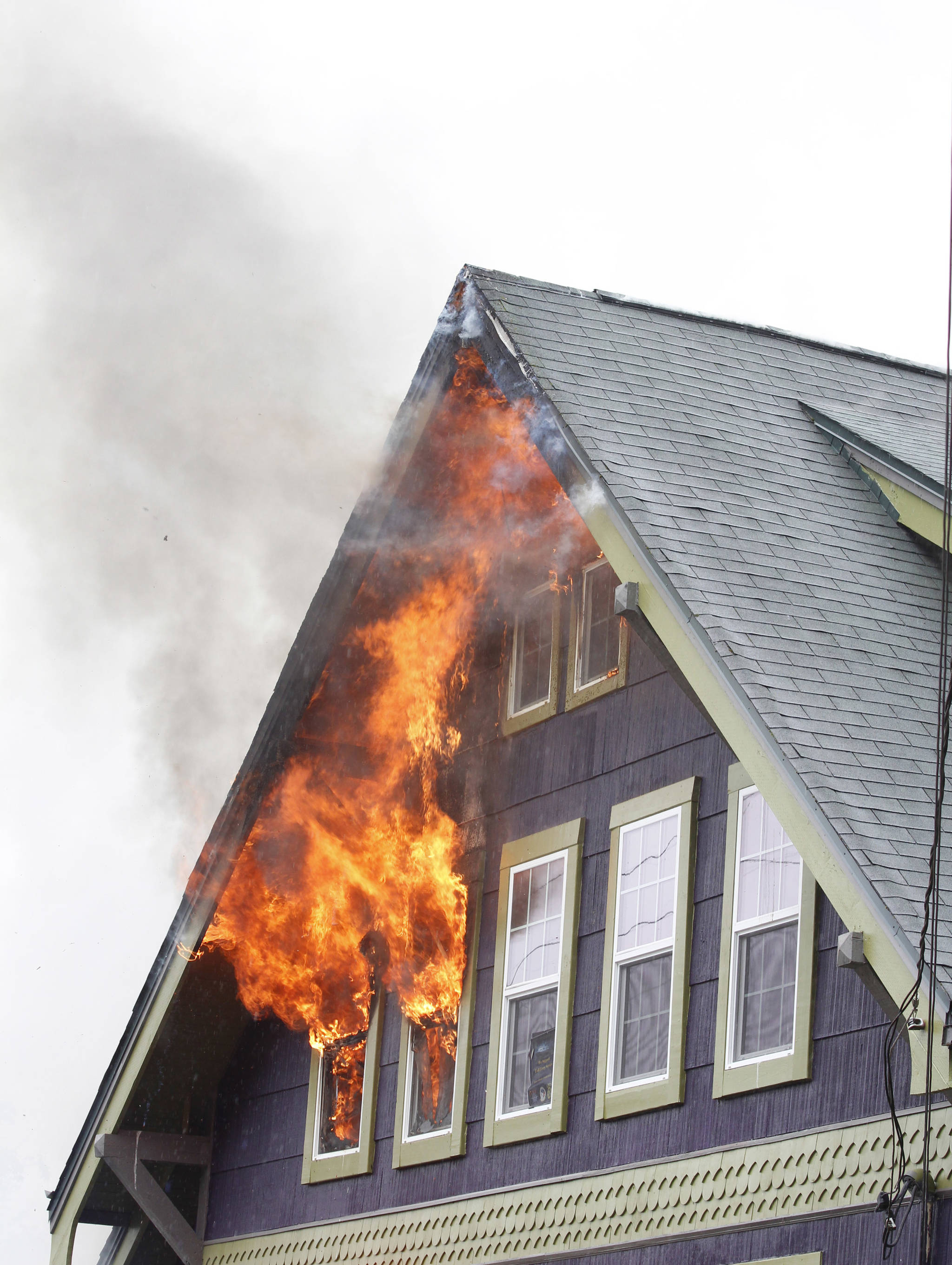 Flames come from windows on the third floor of a house at 505 N. Franklin Street on Monday. The two occupants of the house, along with their dog, escaped unharmed. (Alex McCarthy | Juneau Empire)