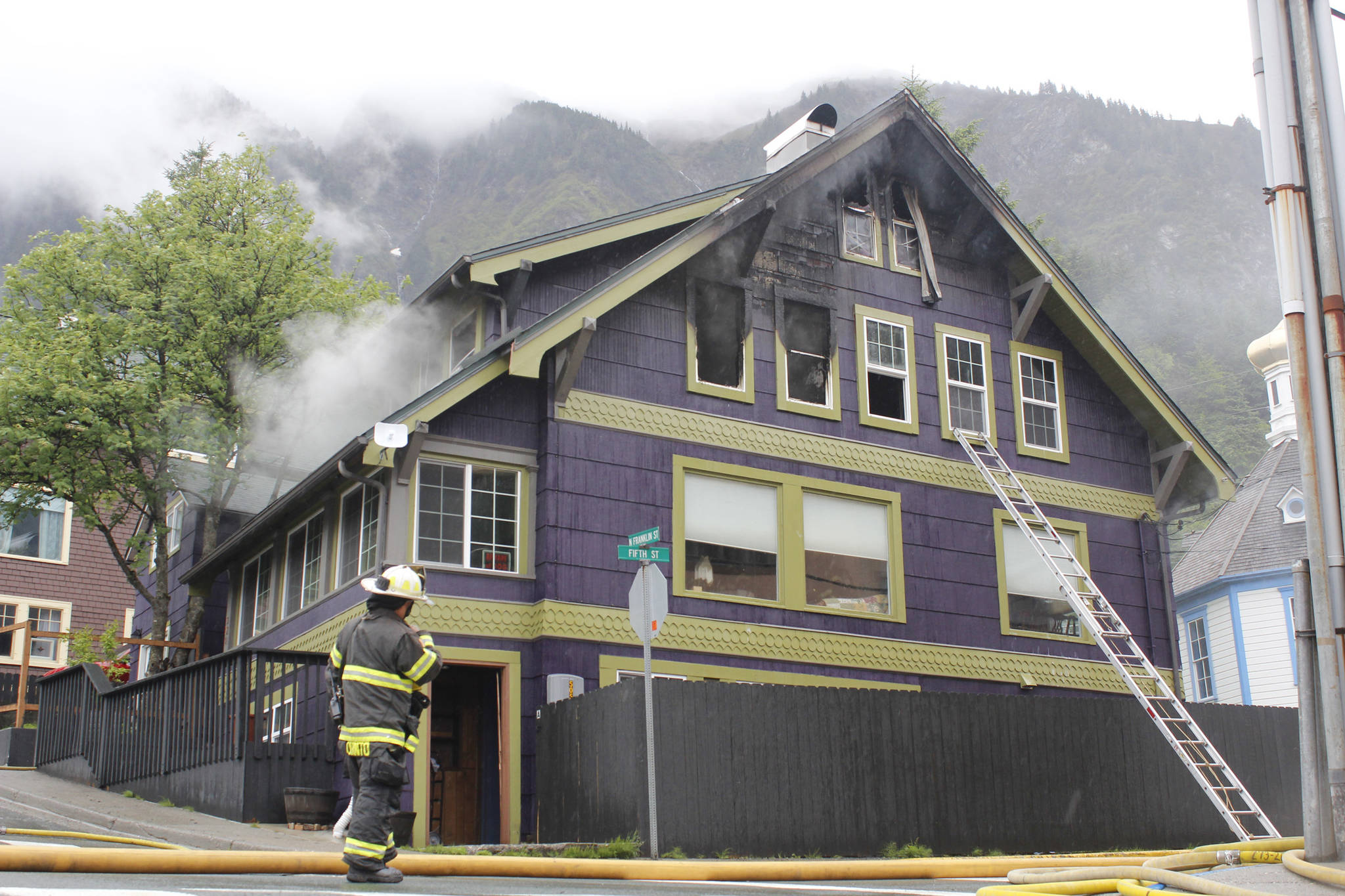 Capital City Fire/Rescue firefighters enter a home at the corner of Fifth and Franklin Streets on Monday to put out smaller fires after knocking down the flames. (Alex McCarthy | Juneau Empire)