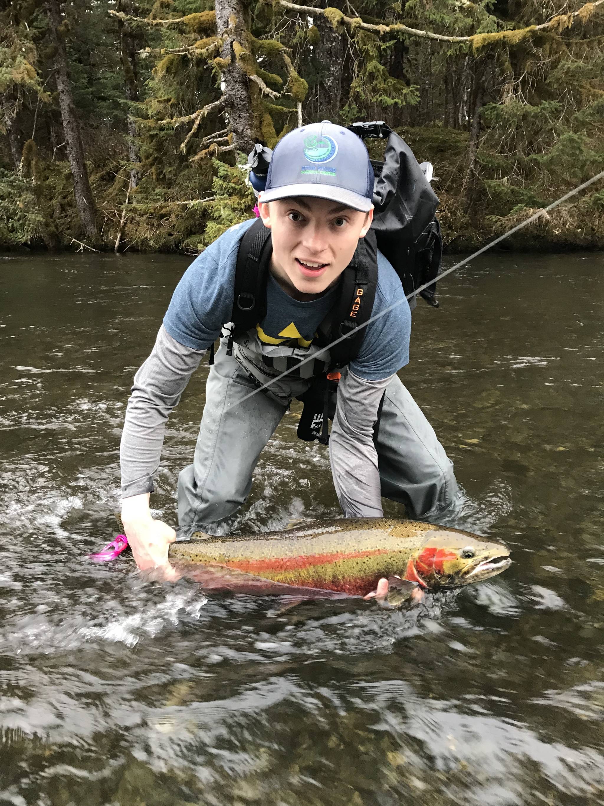 Nick Whicker poses on May 10, 2018 with his first steelhead, caught on the Situk River in Yakutat with a UAS Outdoors studies class taught by professor and Salmon Fellow Kevin Maier. The fish bit onto a fly Whicker had tied that morning (it already had a hook in its tail.) (Photo by Triston Chaney)