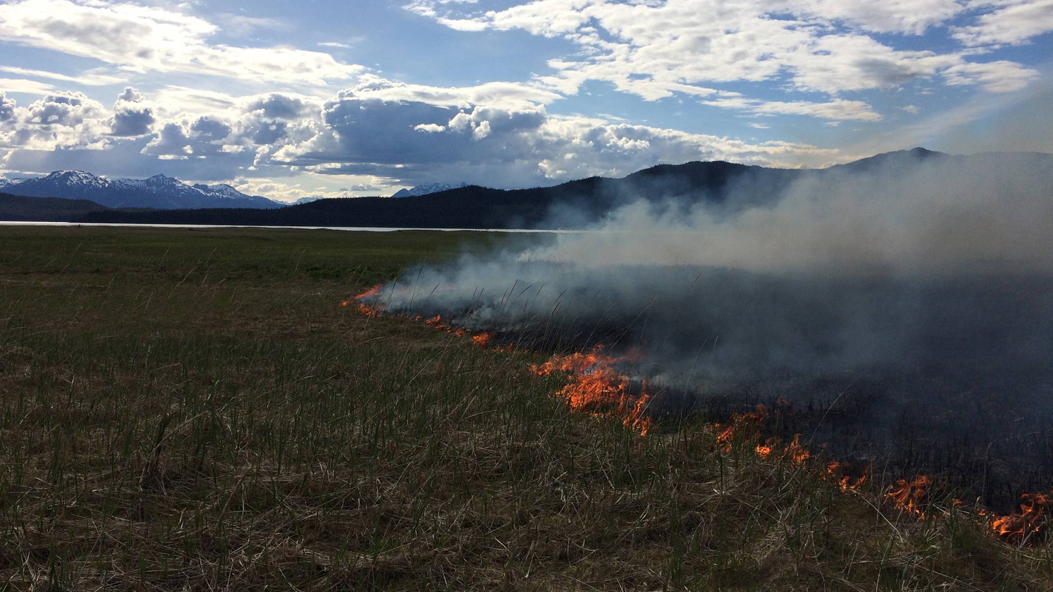 A fire burns on the grass at Antler Flats, in the northeast section of Berners Bay. (Photo courtesy U.S. Forest Service)