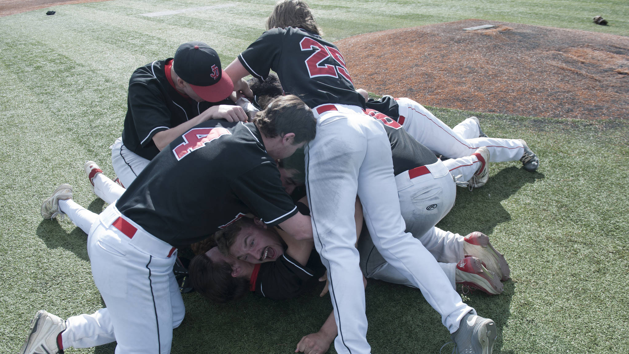 A pig pile for Juneau-Douglas High School pitcher Kasey Watts. The Crimson Bears won the ASAA state baseball championships over South Anchorage 3-2 on Saturday. (Michael Dinneen | For the Juneau Empire)