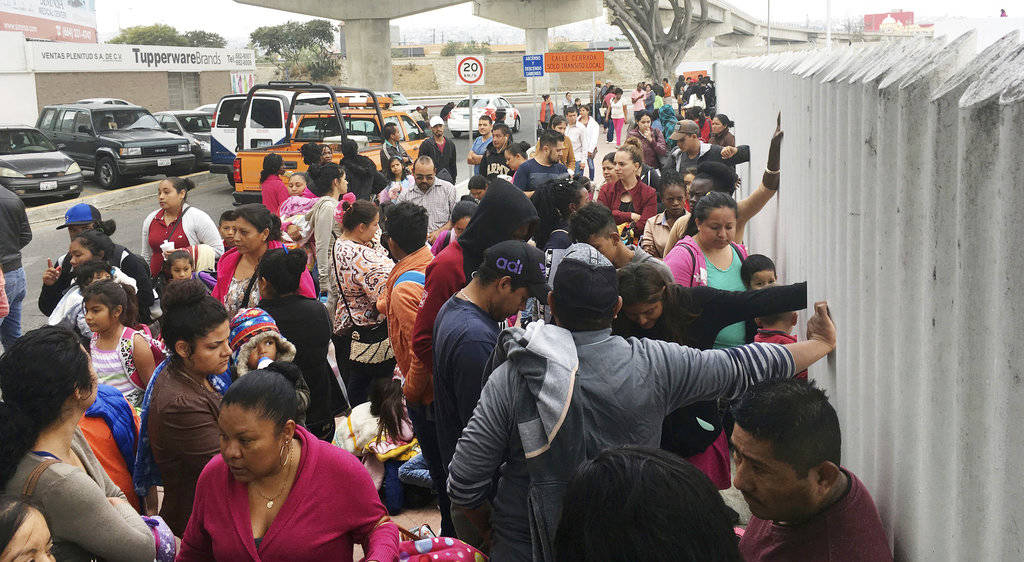 In this Monday, June 4, 2018 photo, people seeking political asylum in the United States line up to be interviewed in Tijuana, Mexico, just across the U.S. border south of San Diego. The Trump administration’s fighting words for asylum seekers don’t appear to be having much impact at U.S. border crossings with Mexico. Lines keep growing, so much that U.S. authorities can’t take them all at once. (AP Photo/Elliot Spagat)