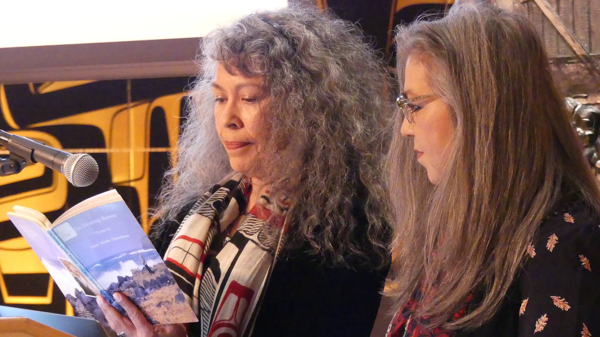 Donna Beaver and Rhonda Mann review a poem together from Nora Dauenhauer’s poetry book, “The Droning Shaman.” Beaver and Mann both read poems by Dauenhauer in her honor. Ray Friedlander | For the Capital City Weekly