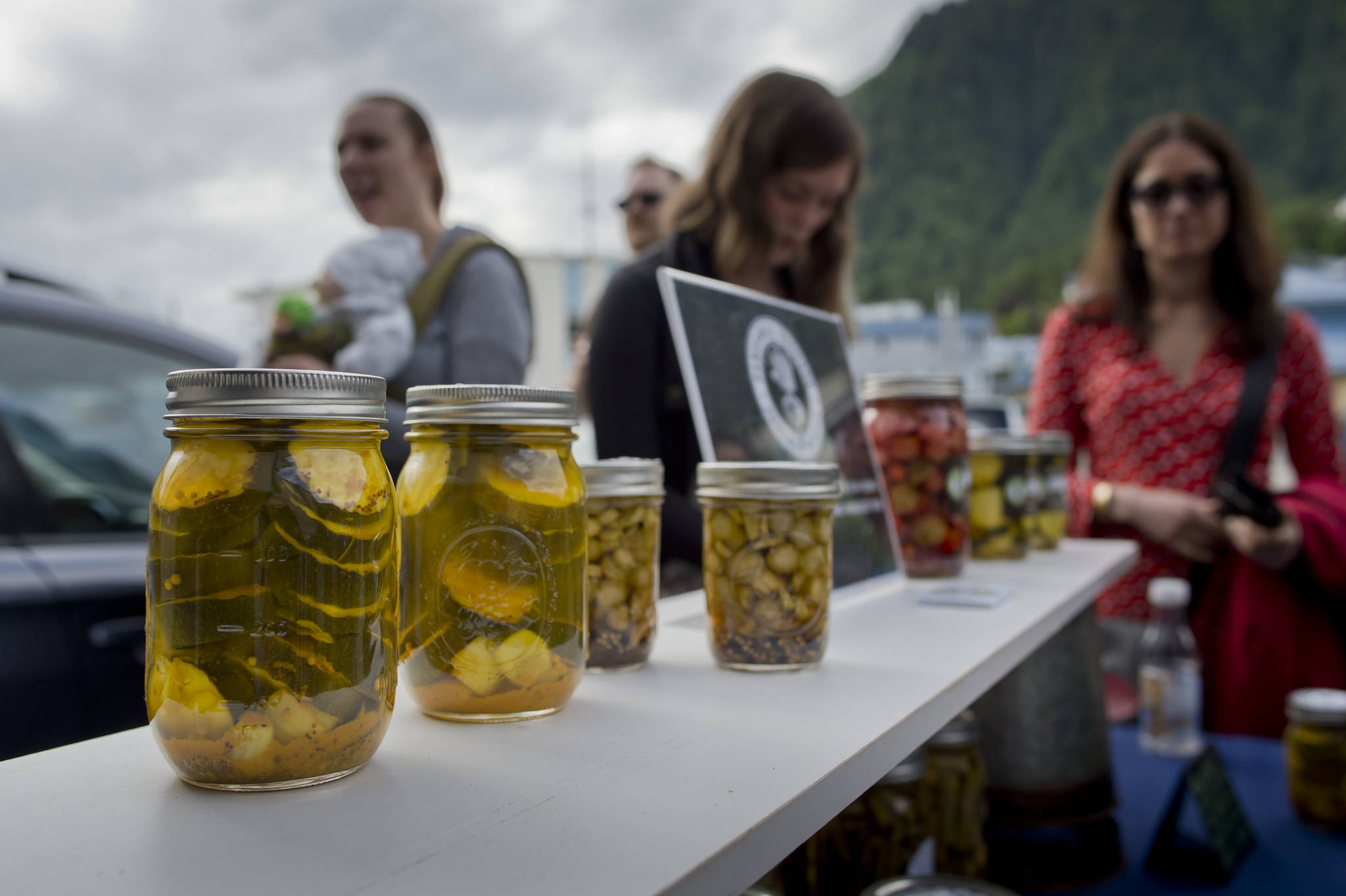 Kylie Wray, of Panhandle Produce, center, sells pickled vegetables during the Block Party at the Juneau Arts & Culture Center on Friday, June 15, 2018. (Michael Penn | Juneau Empire)