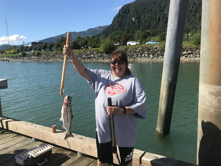 Priscilla Jordan holds up a king salmon caught at Wayside Dock Monday afternoon. (Gregory Philson | Juneau Empire)