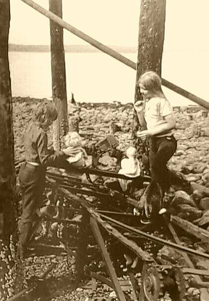 The author (right) and her sister Megan (left) playing with baby dolls in the scorched remains of the old cannery.