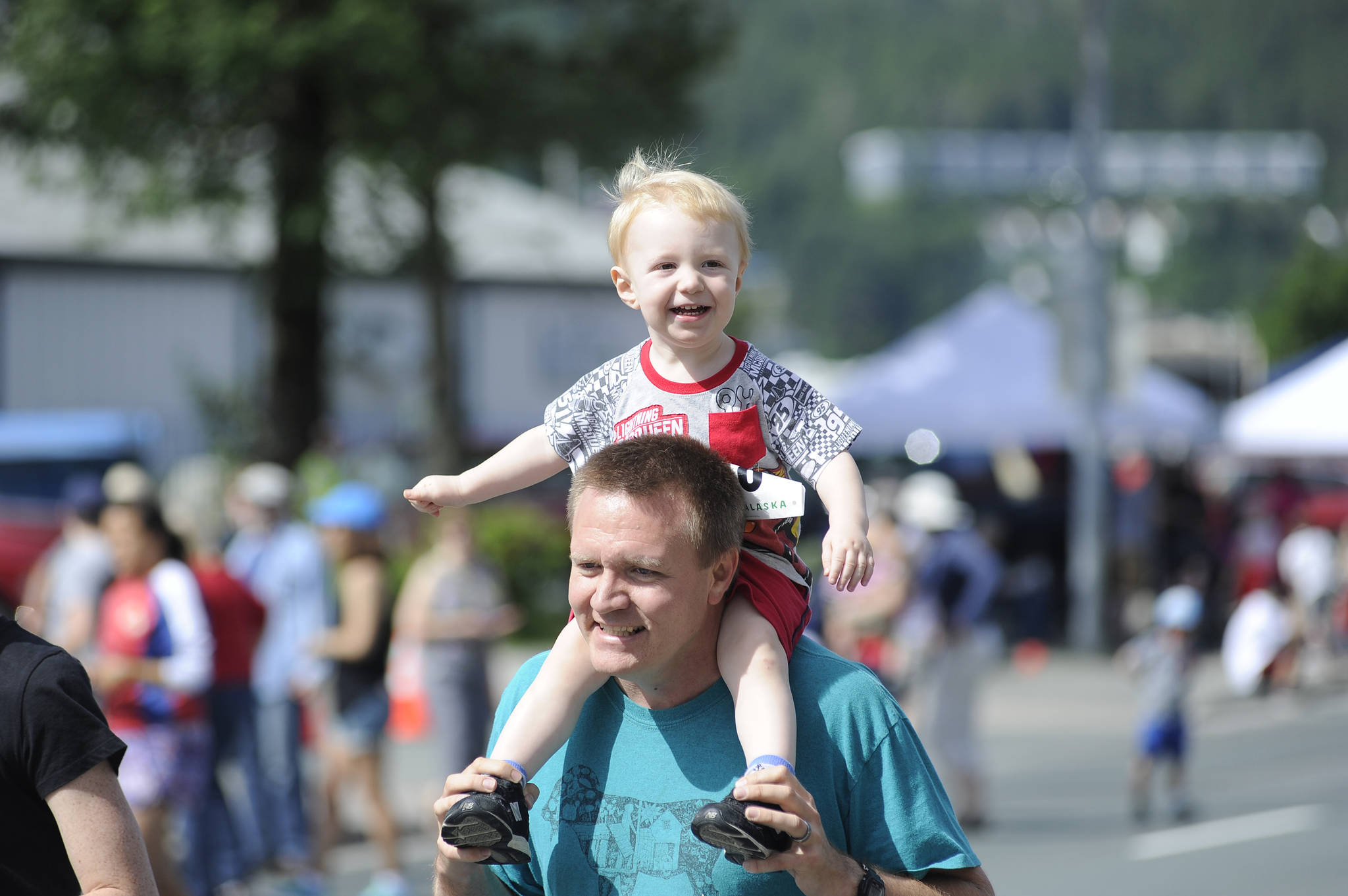 Myron Davis carries his son during the start of the Glenn Frick Memorial Mile, which took place just before the start of the Juneau Fourth of July Parade on Wednesday. (Nolin Ainsworth | Juneau Empire)