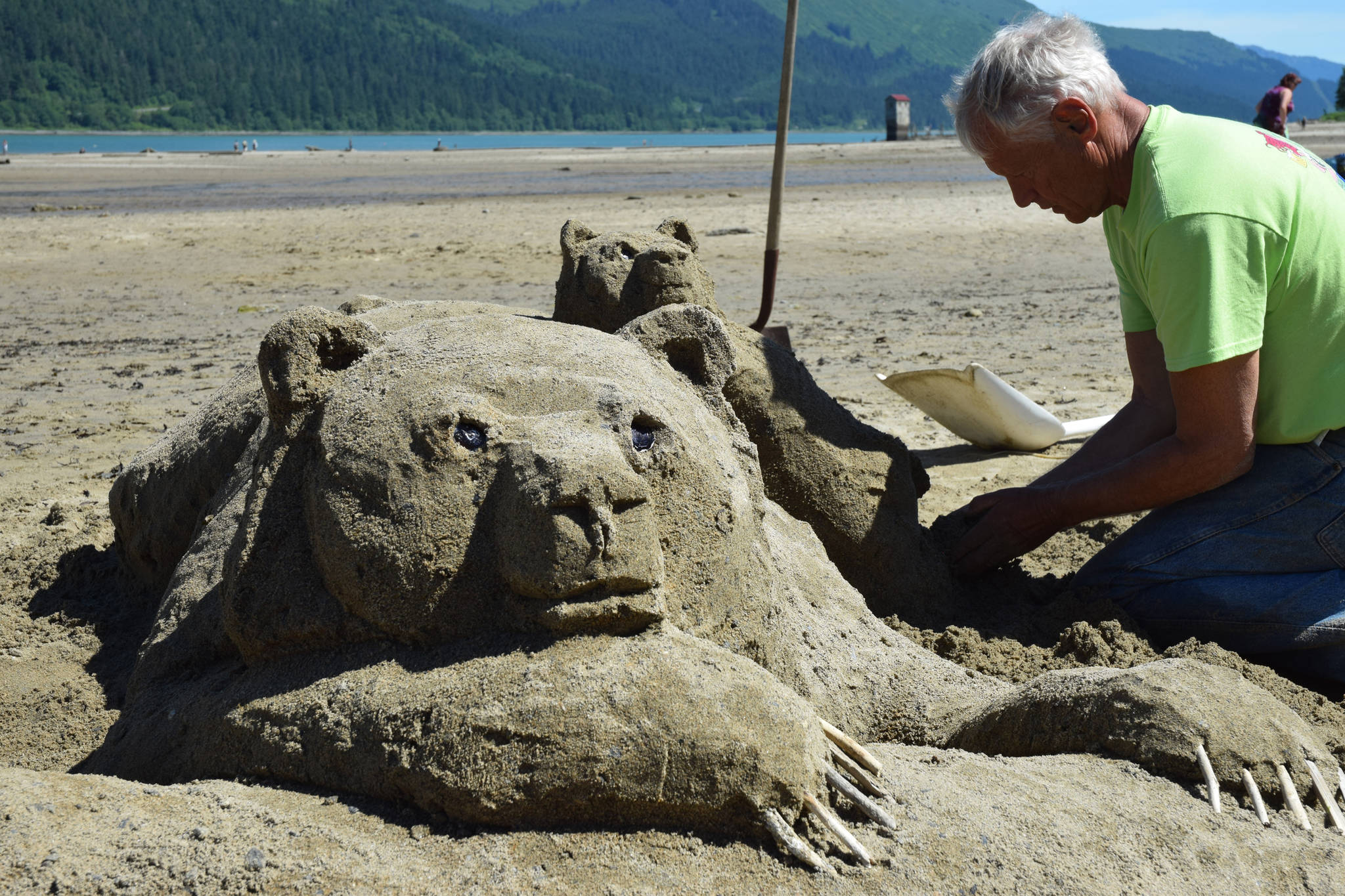 Lee Stoops works on a brown bear and cub sand sculpture Wednesday during a sand sculpting contest at Sandy Beach. (Kevin Gullufsen | Juneau Empire)