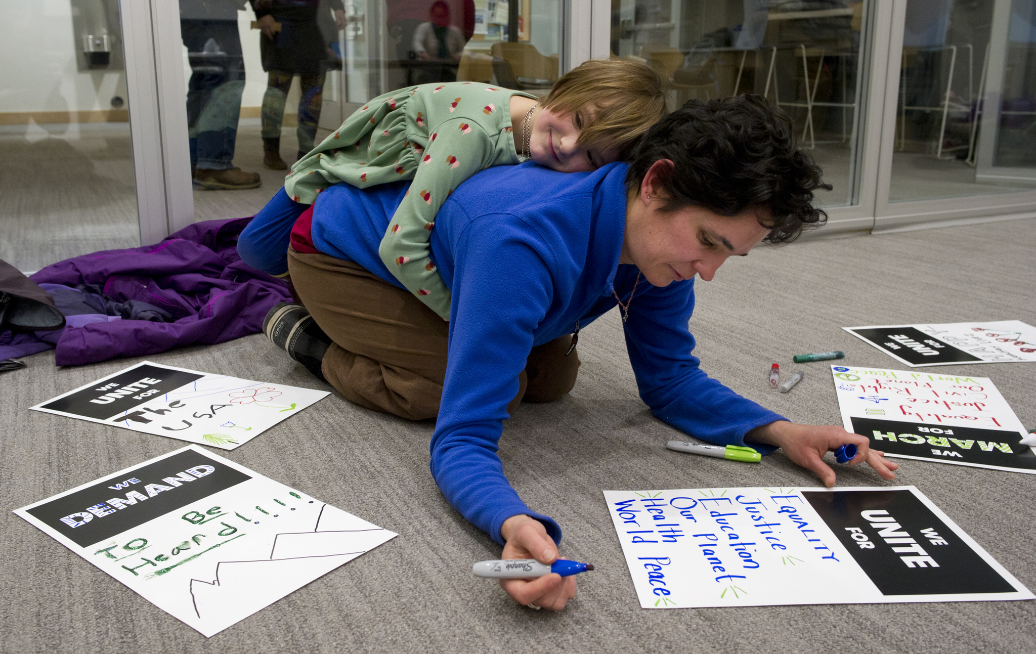 Eleanor Cullum, 6, stays close to her mom, Melissa, as they work on posters at the Mendenhall Public Library on Thursday for Saturday’s Women’s March on Juneau. The event starts at the Alaska State Capitol steps at 9 a.m. and finishes at the Juneau Arts & Culture Center. (Michael Penn | Juneau Empire)